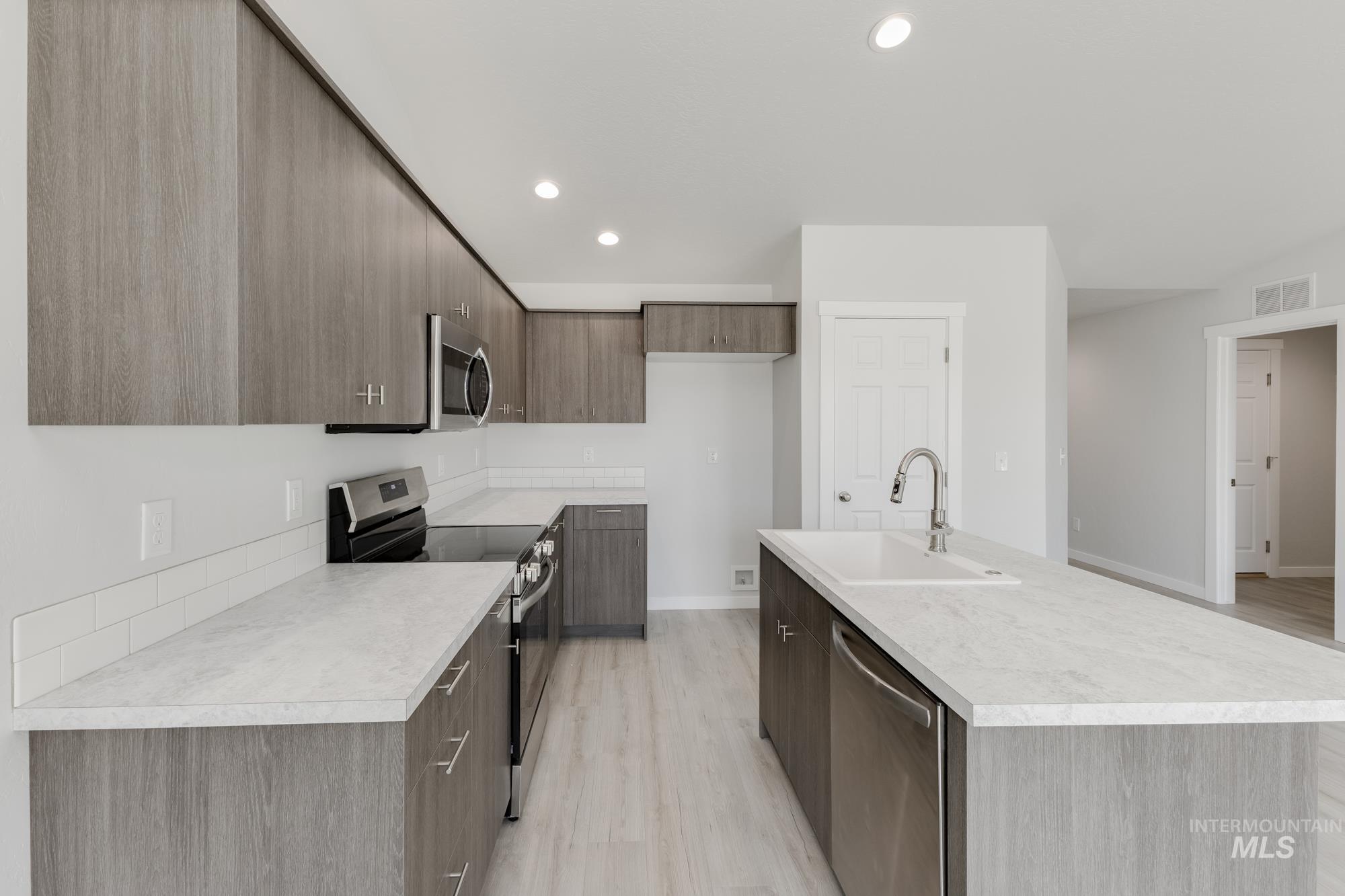 Kitchen featuring modern cabinets, stainless steel appliances, recessed lighting, light wood-style flooring, and light countertops