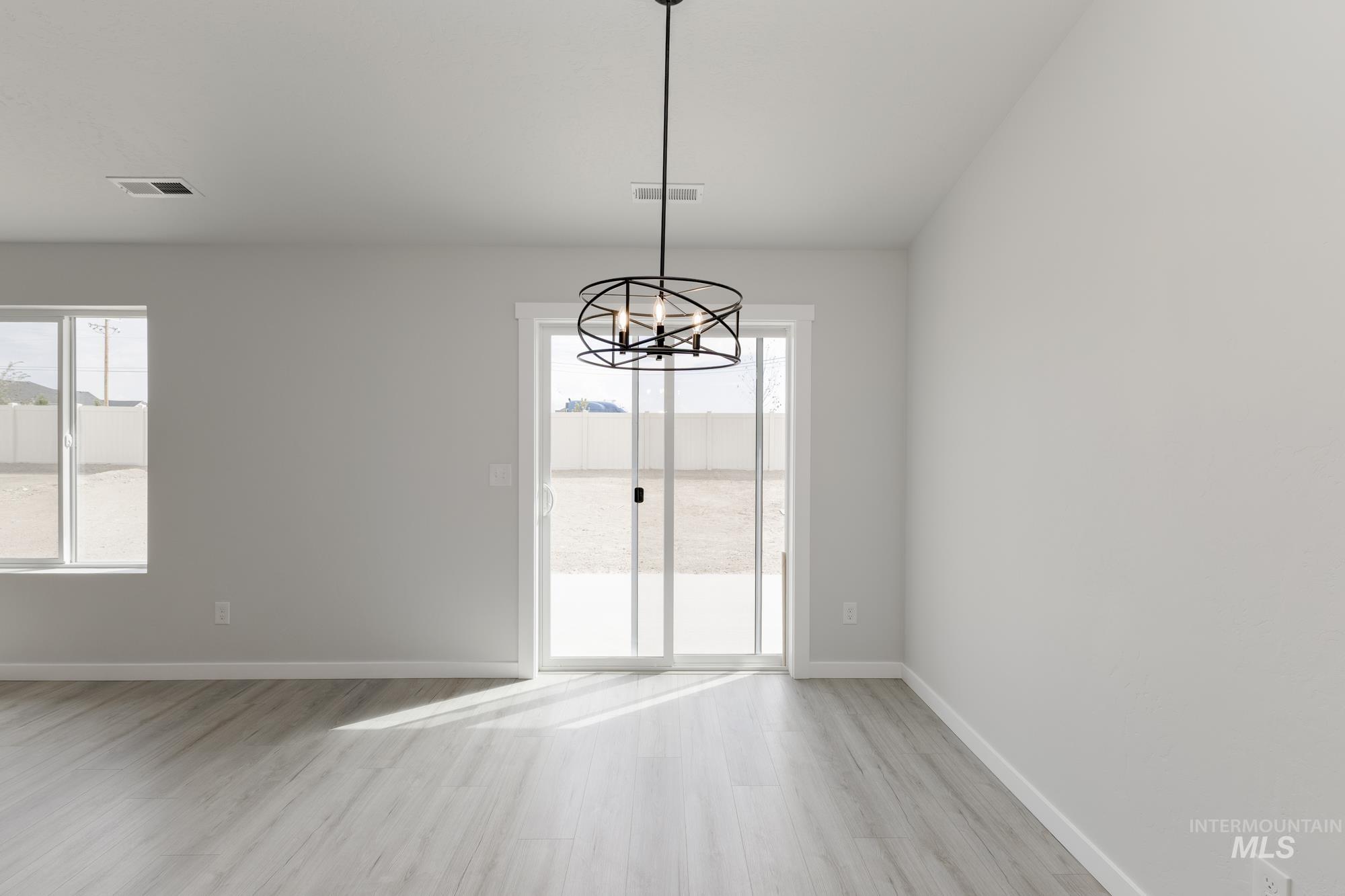 Spare room with plenty of natural light, light wood finished floors, and a chandelier