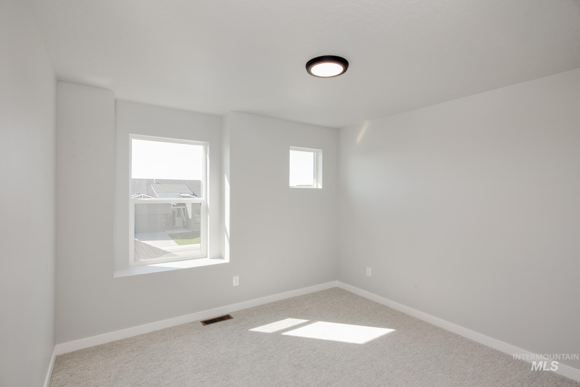 Carpeted spare room featuring baseboards