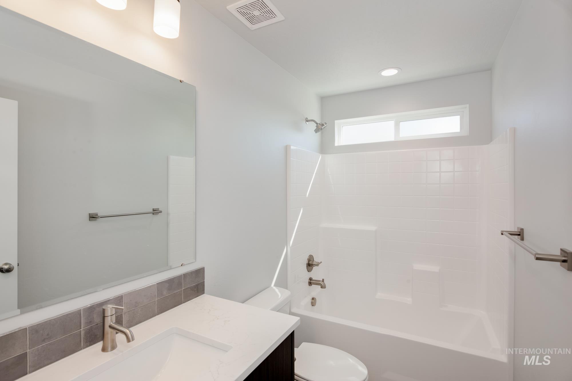 Bathroom with vanity, washtub / shower combination, and backsplash