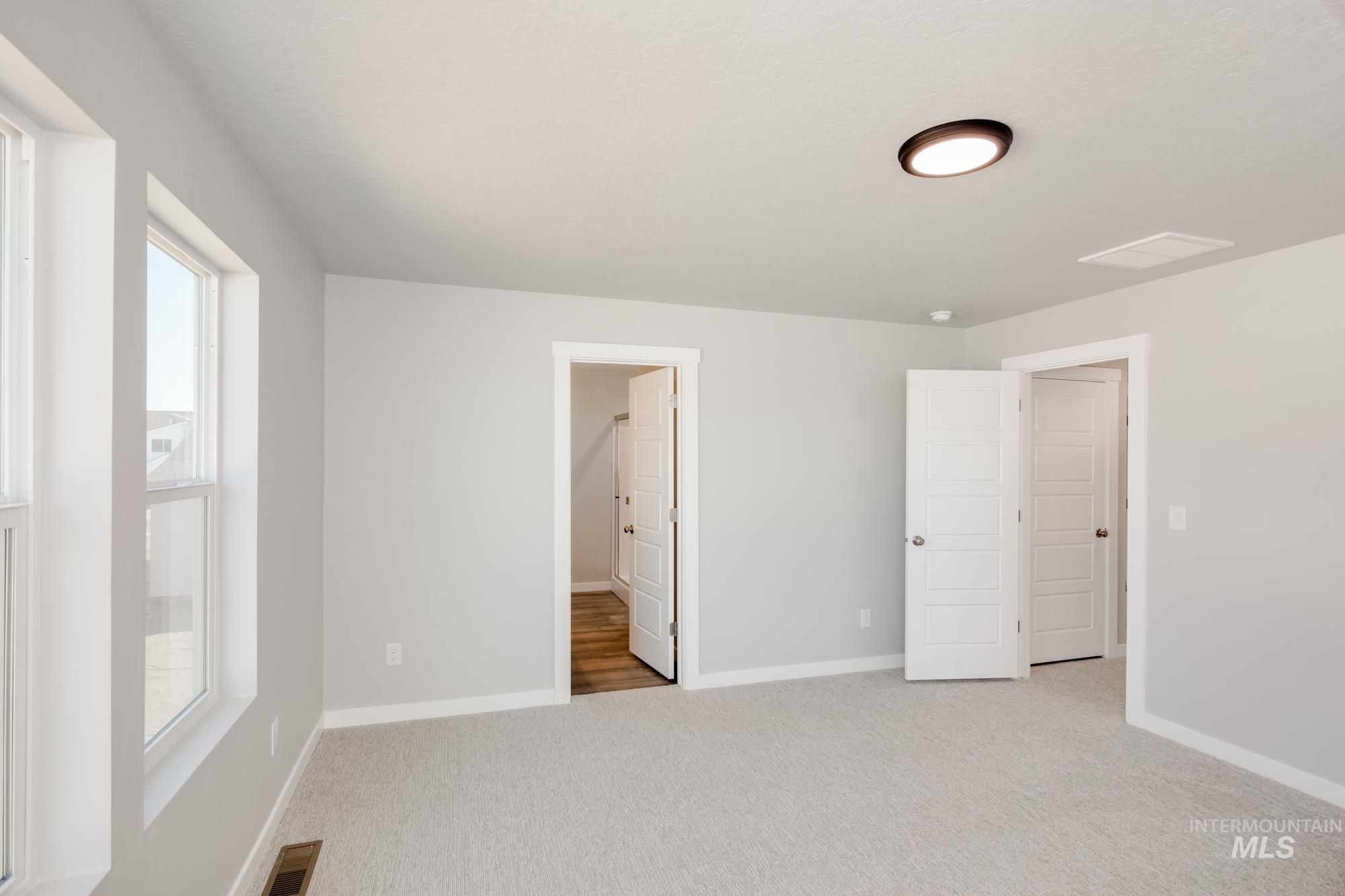 Unfurnished bedroom featuring light carpet and baseboards