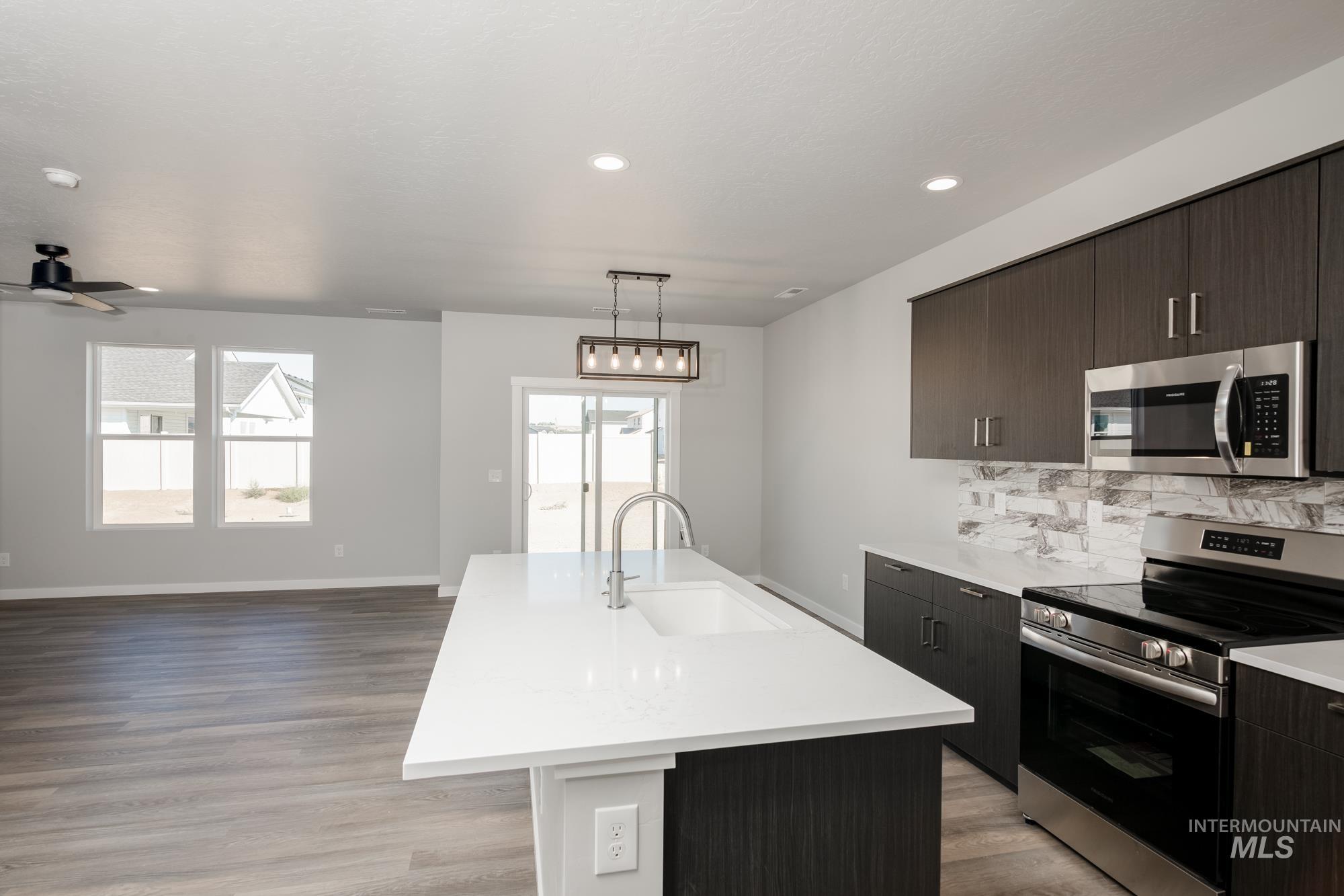 Kitchen featuring stainless steel appliances, plenty of natural light, light countertops, an island with sink, and recessed lighting