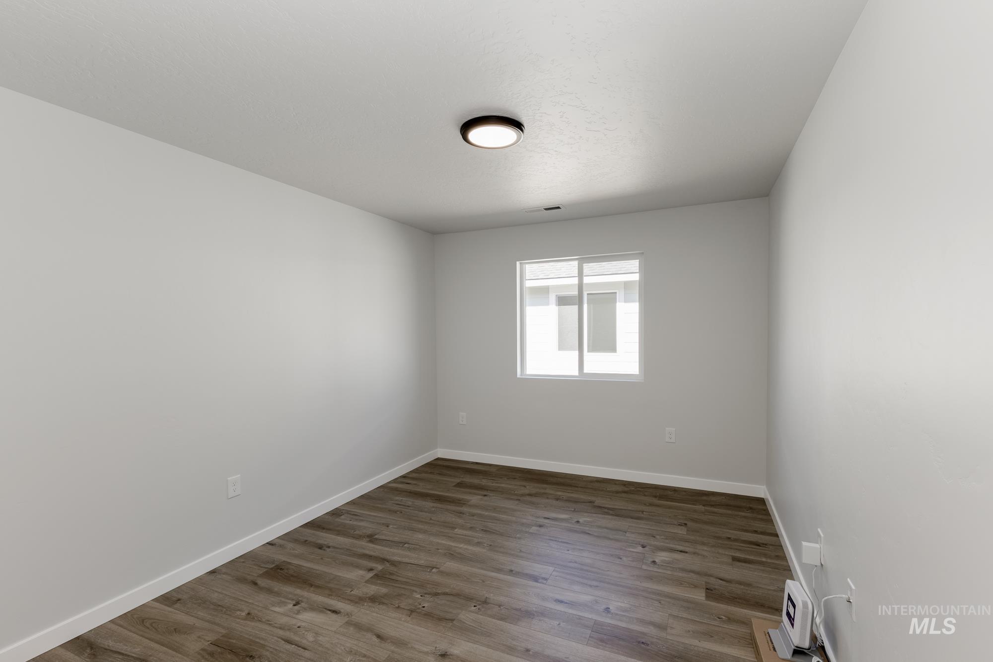 Spare room with dark wood finished floors and baseboards
