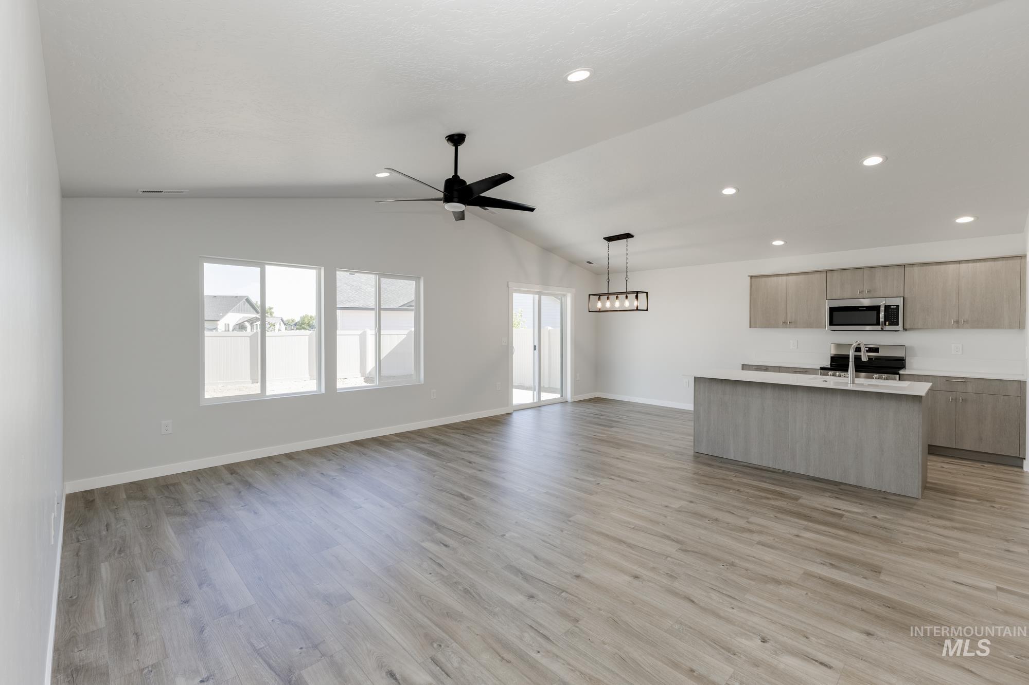 Kitchen featuring open floor plan, an island with sink, lofted ceiling, light wood-type flooring, and modern cabinets