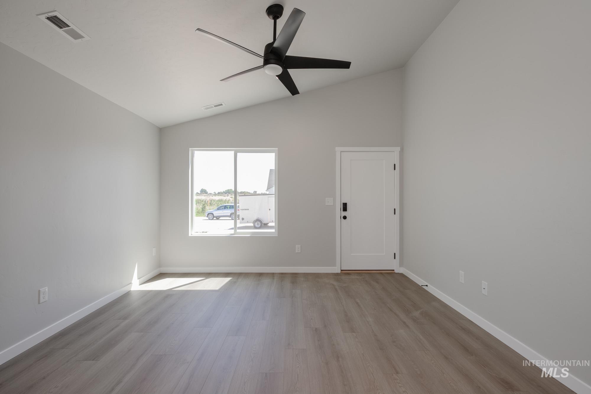 Spare room with vaulted ceiling, wood finished floors, and ceiling fan
