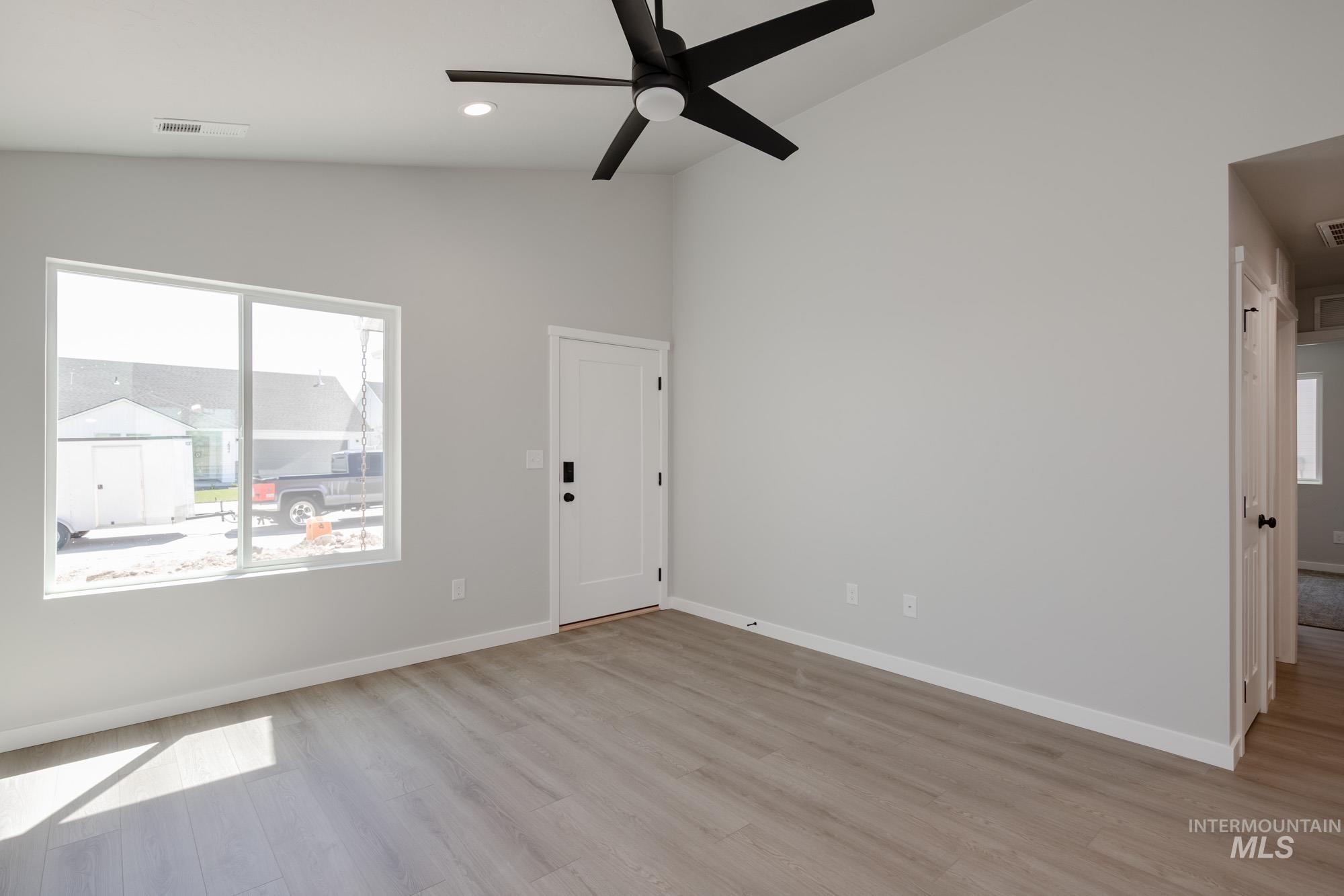 Spare room featuring healthy amount of natural light, light wood-style flooring, ceiling fan, recessed lighting, and high vaulted ceiling