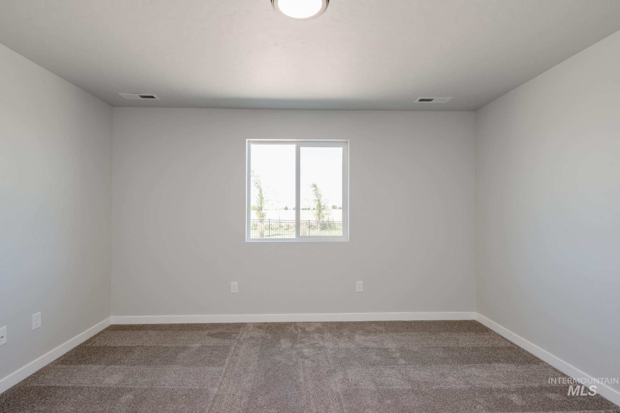 Empty room featuring light colored carpet and baseboards