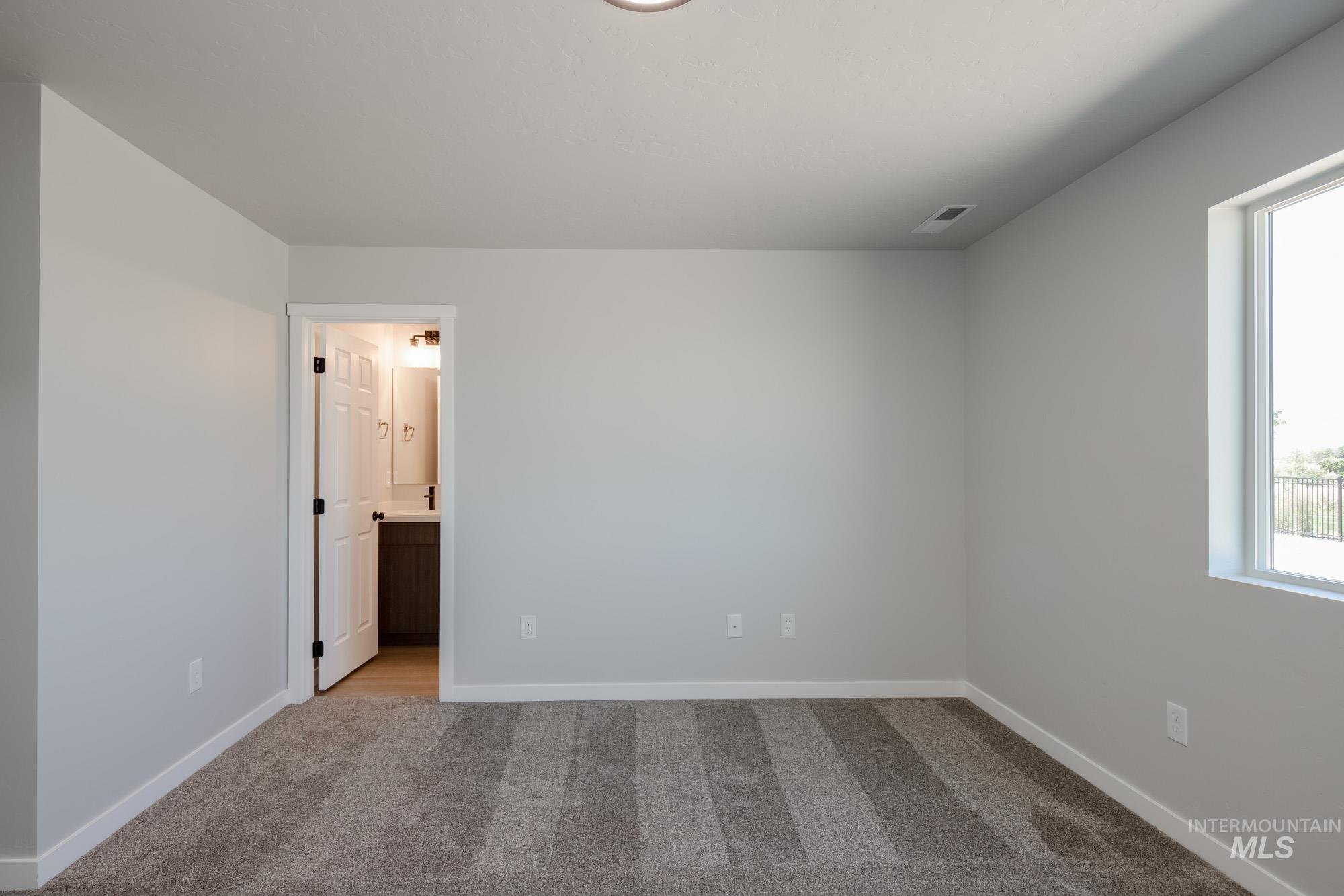 Unfurnished bedroom featuring light colored carpet and ensuite bathroom