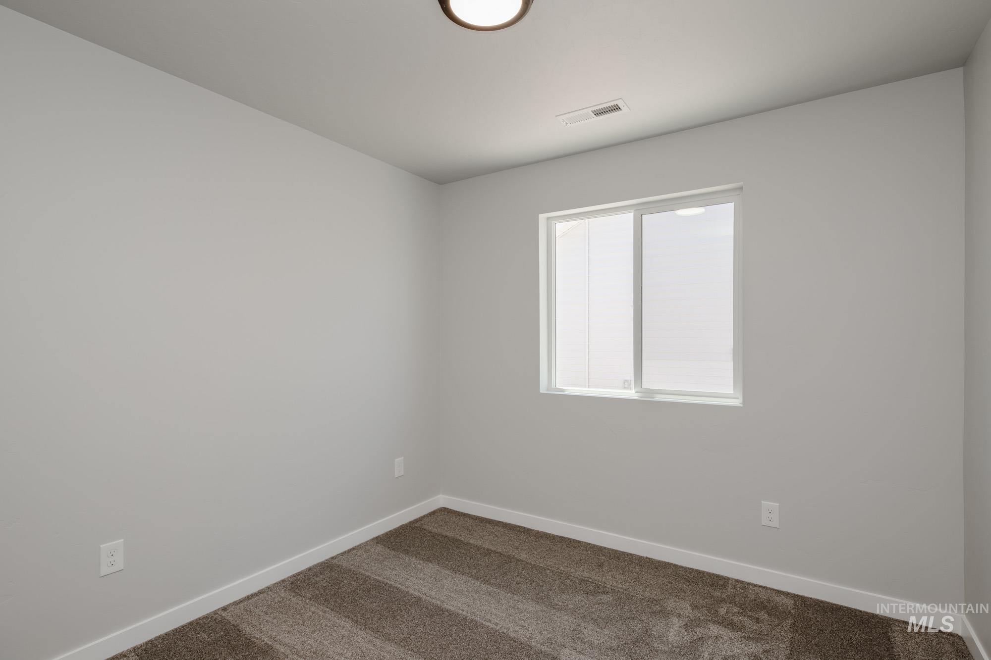 Spare room featuring carpet floors and baseboards