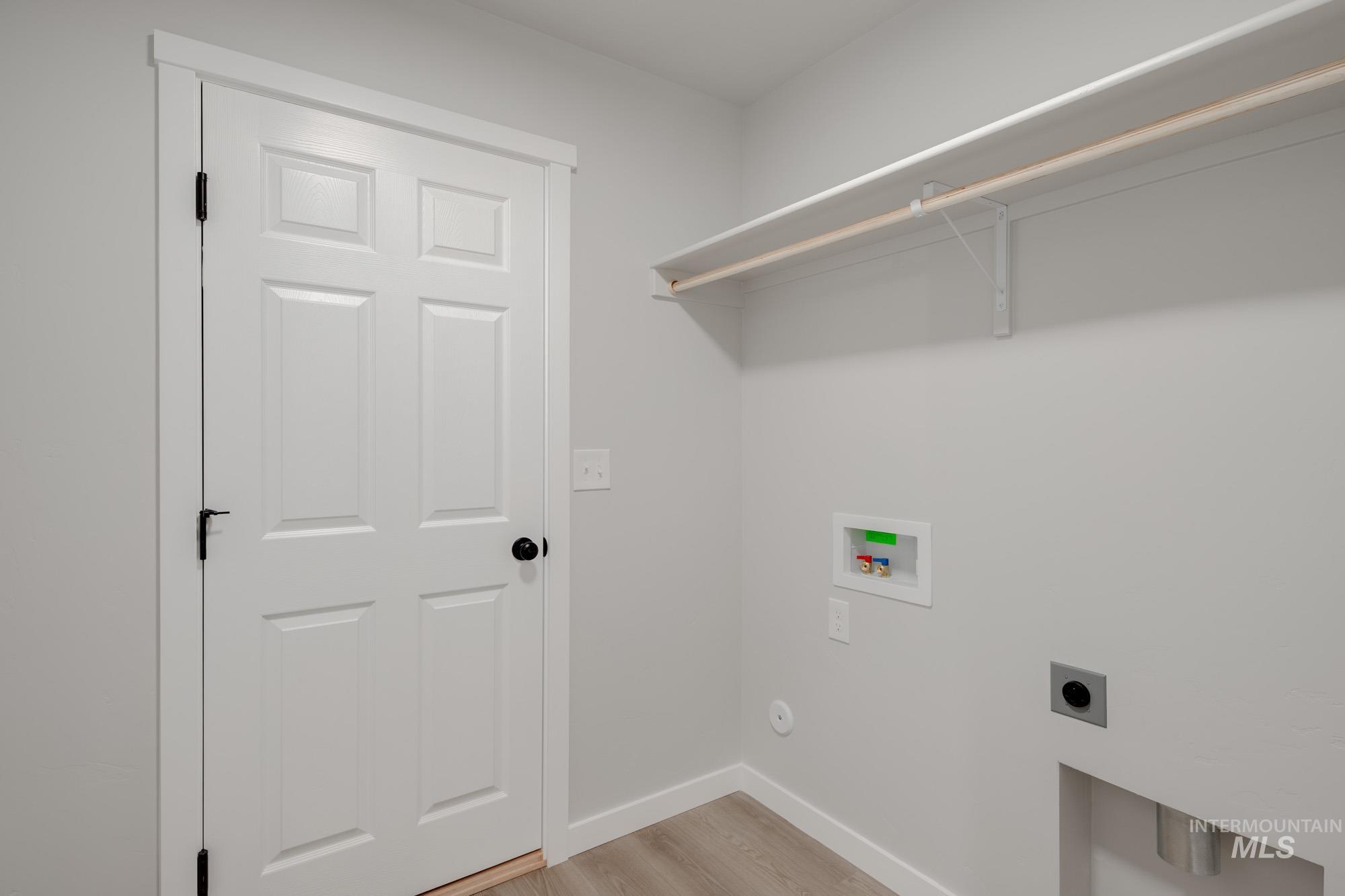 Laundry room with light wood-style floors, hookup for an electric dryer, and hookup for a washing machine