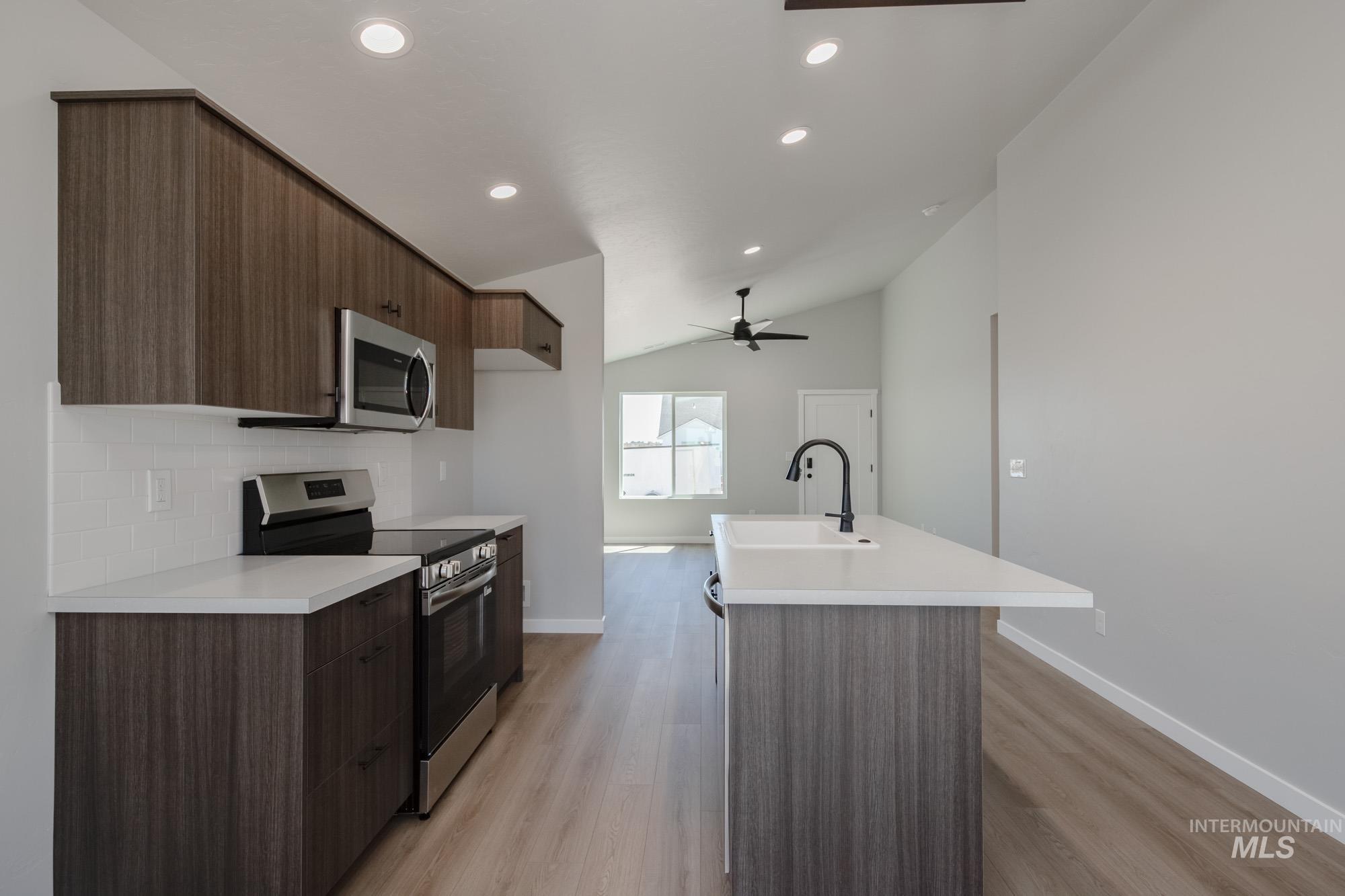 Kitchen featuring appliances with stainless steel finishes, modern cabinets, light countertops, an island with sink, and recessed lighting