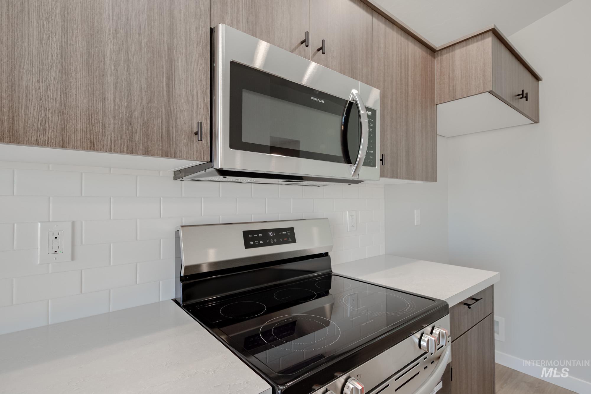 Kitchen with stainless steel appliances, modern cabinets, backsplash, and light wood finished floors