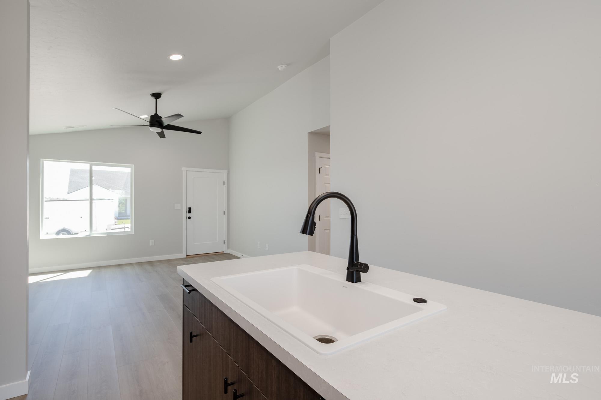 Kitchen with lofted ceiling, light wood finished floors, dark brown cabinets, a ceiling fan, and recessed lighting