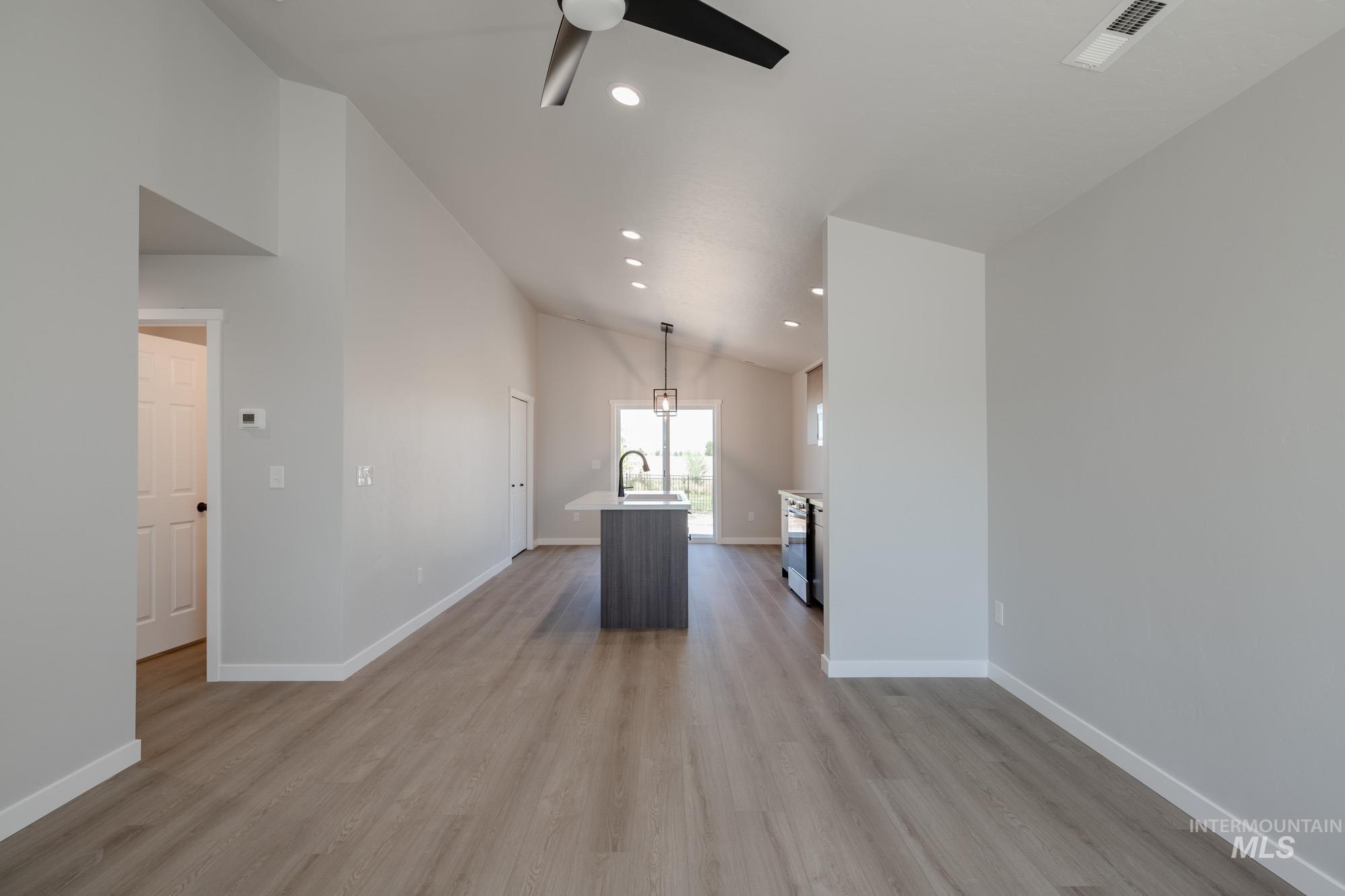 Kitchen with a kitchen island with sink, decorative light fixtures, light wood-style flooring, recessed lighting, and open floor plan