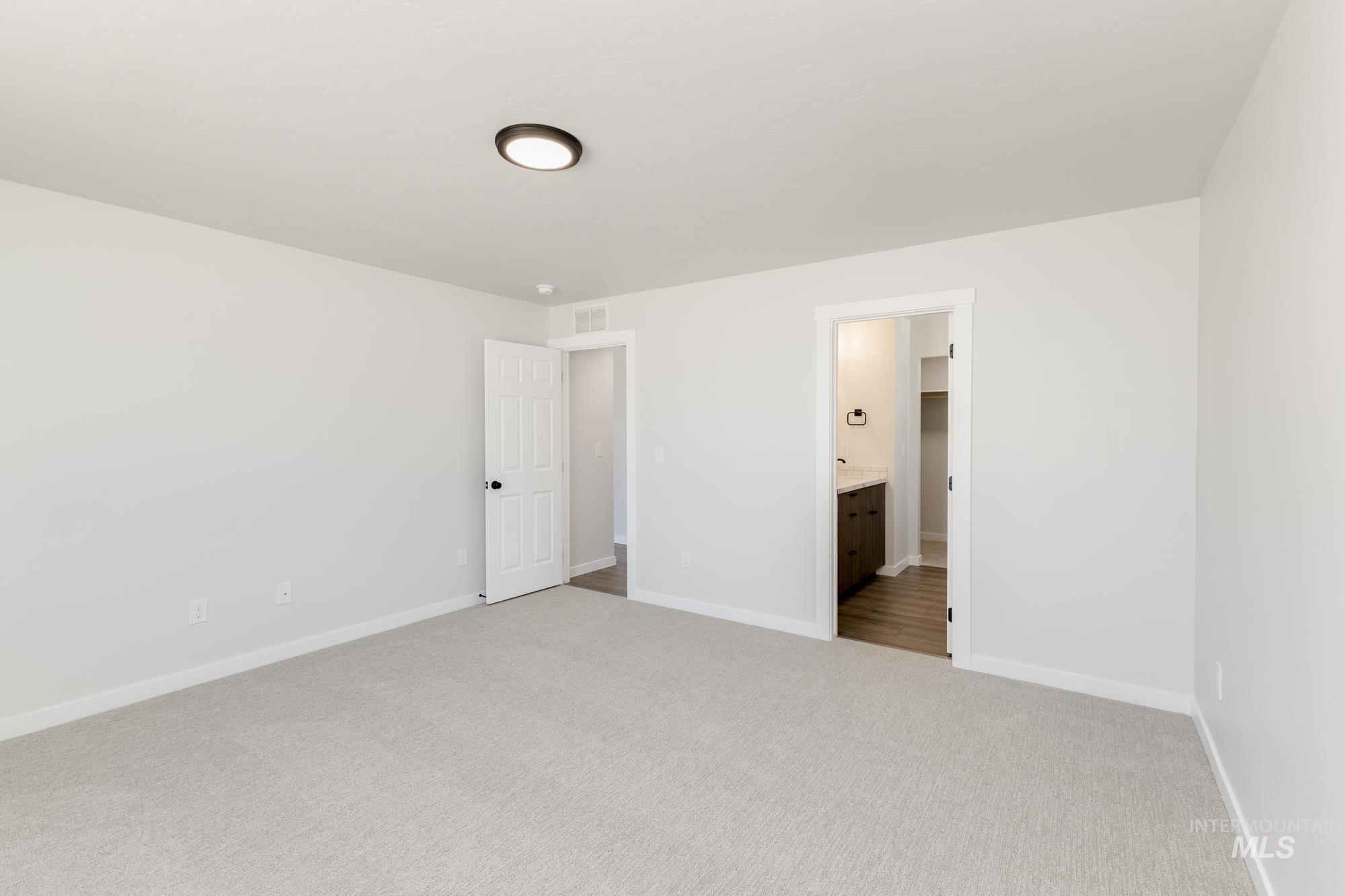 Unfurnished bedroom with light carpet and connected bathroom