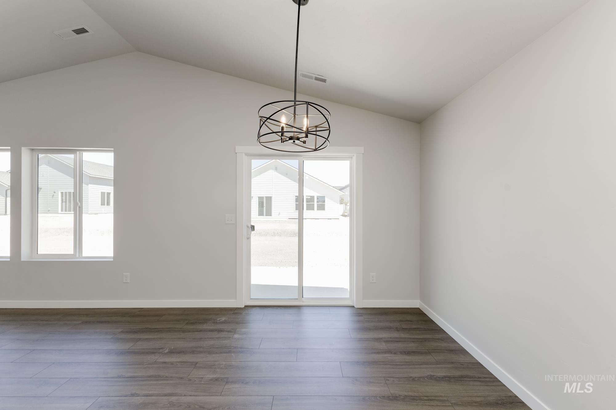Unfurnished dining area with plenty of natural light, a chandelier, dark wood finished floors, and lofted ceiling