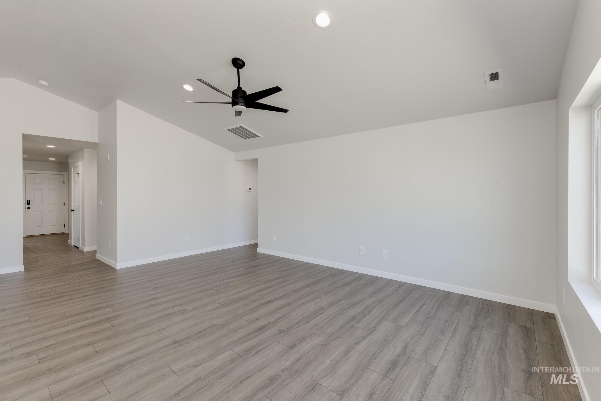 Empty room with lofted ceiling, light wood finished floors, recessed lighting, and ceiling fan