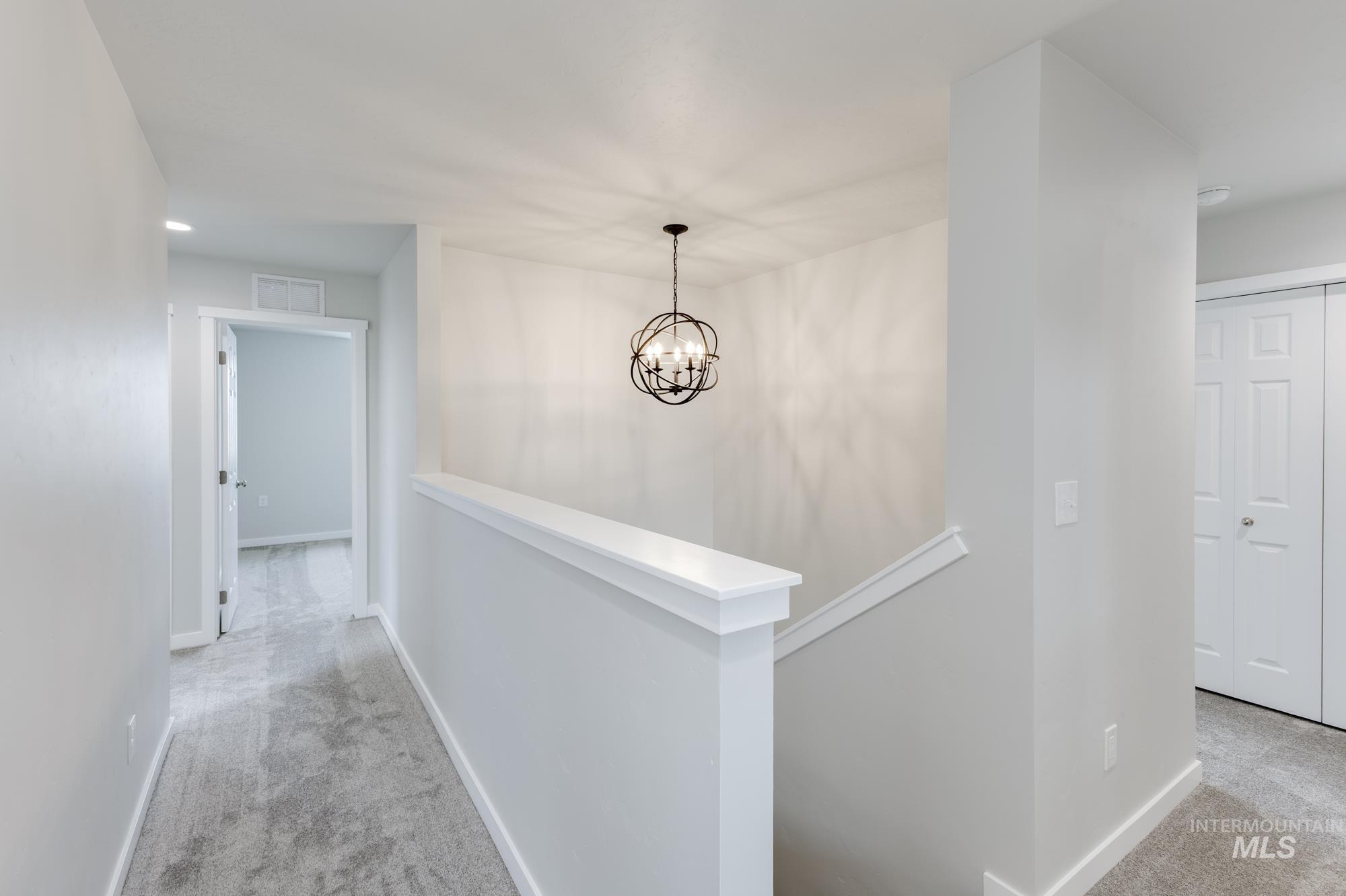 Hall featuring light carpet, an upstairs landing, and a chandelier
