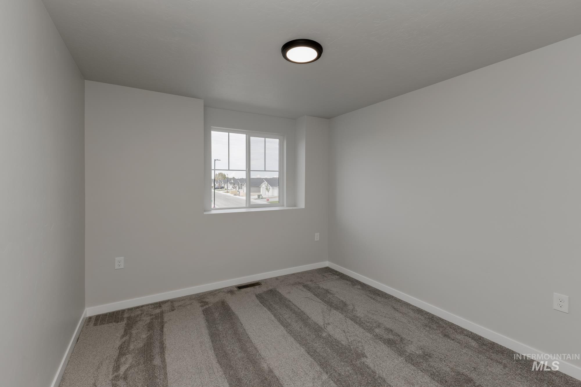 Carpeted empty room featuring baseboards