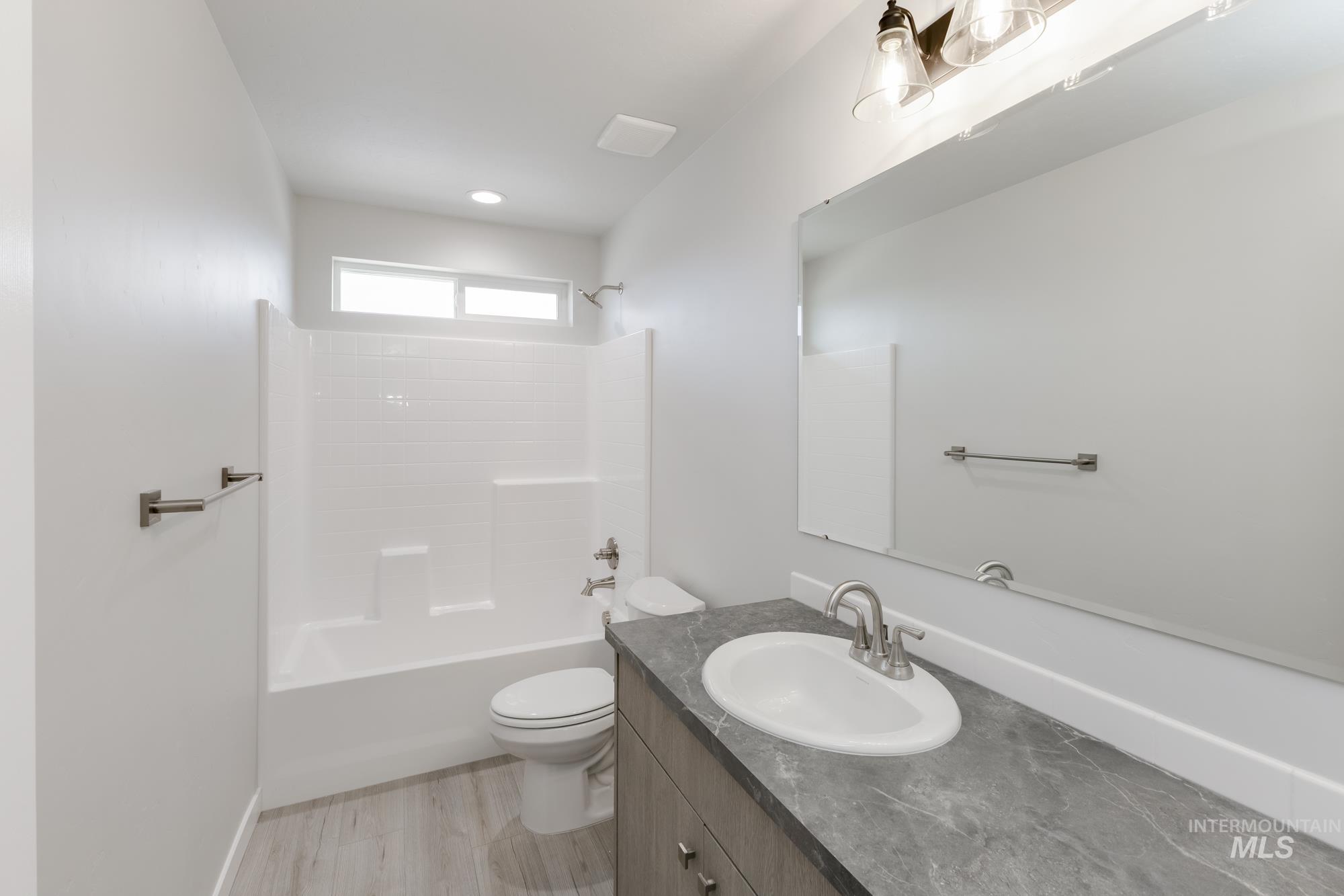 Bathroom with bathtub / shower combination, vanity, and light wood-style flooring