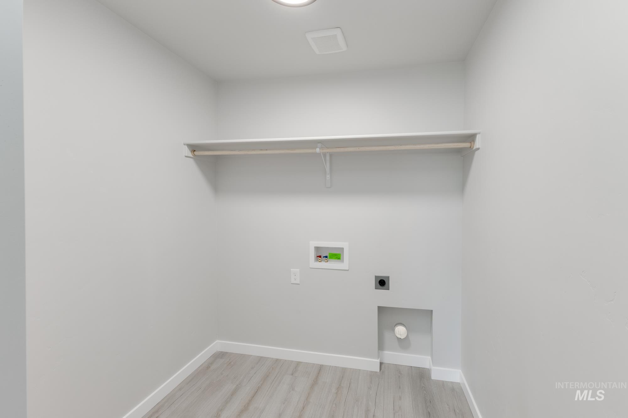 Washroom with light wood-style flooring, hookup for an electric dryer, and hookup for a washing machine