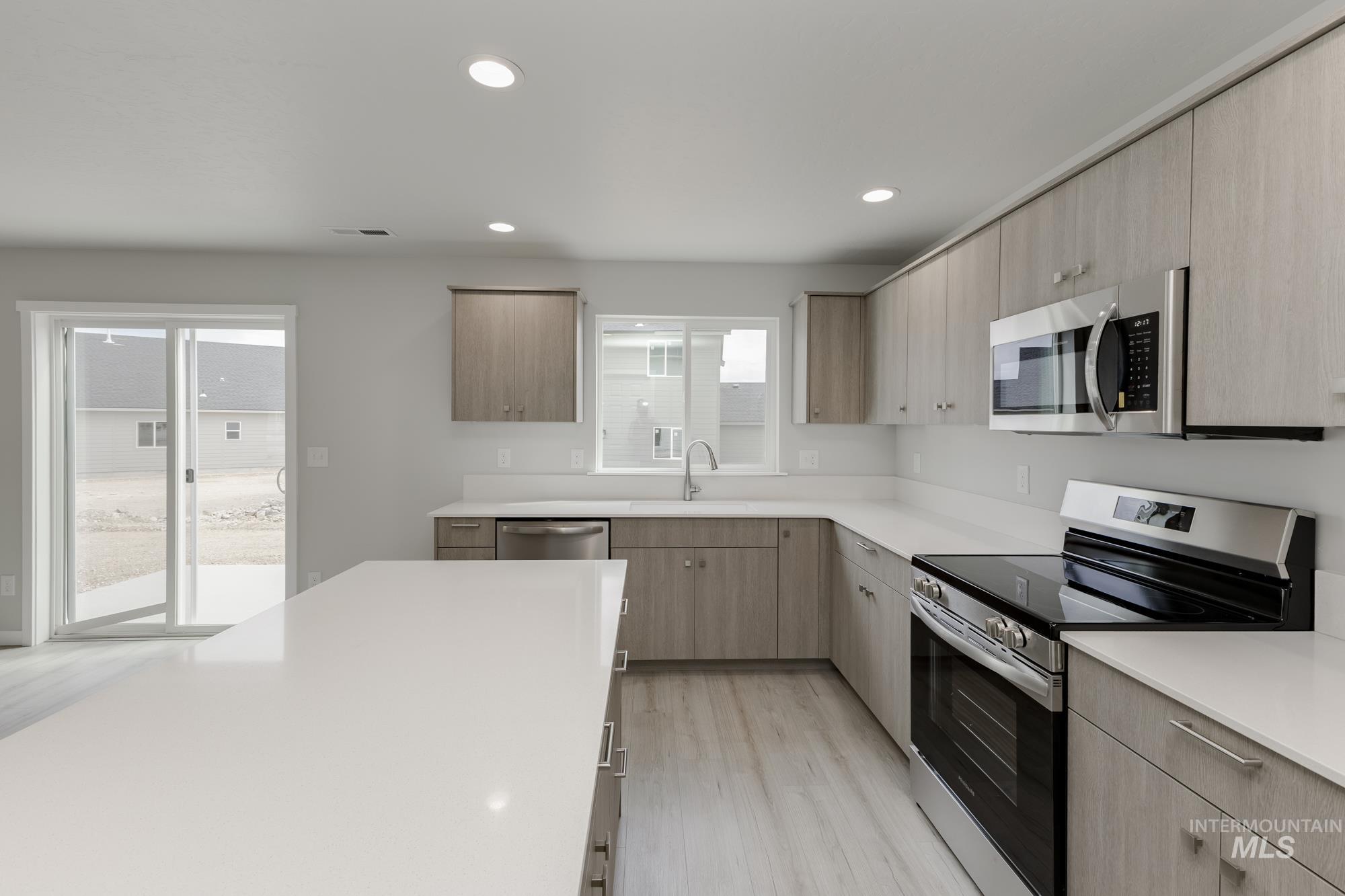 Kitchen featuring stainless steel appliances, light wood-style floors, modern cabinets, recessed lighting, and light brown cabinetry