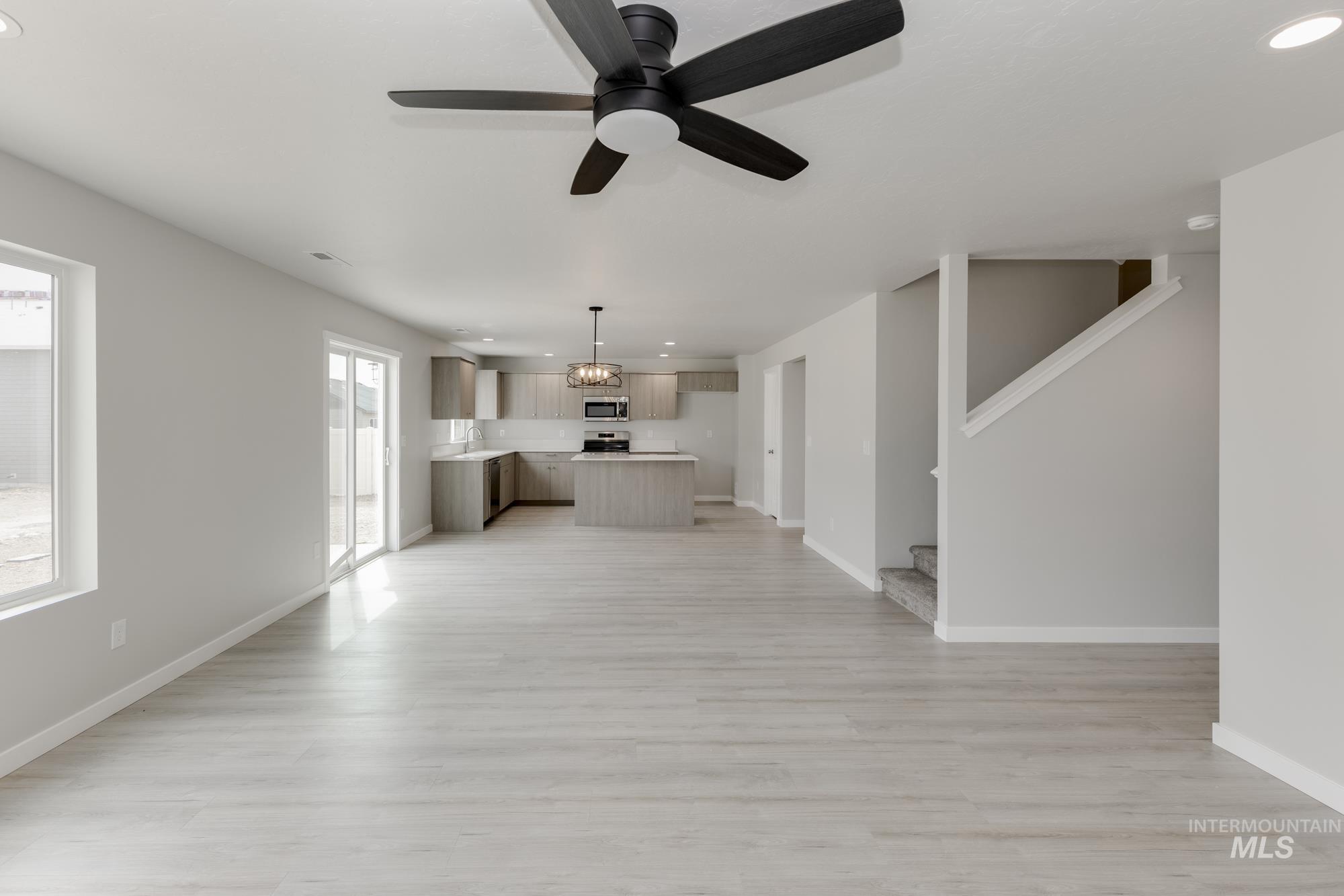 Unfurnished living room featuring recessed lighting, light wood-style floors, ceiling fan, and stairway