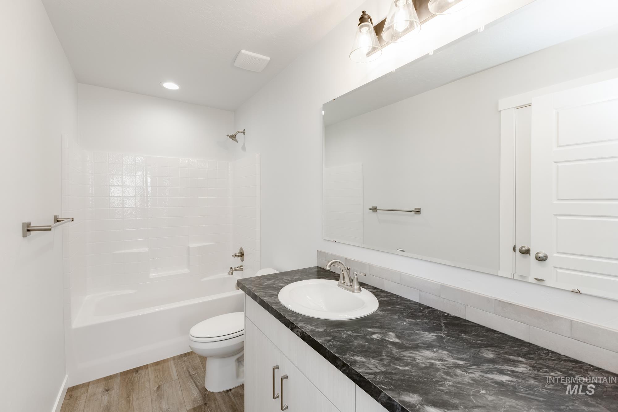 Full bathroom with vanity, shower / washtub combination, wood finished floors, and recessed lighting