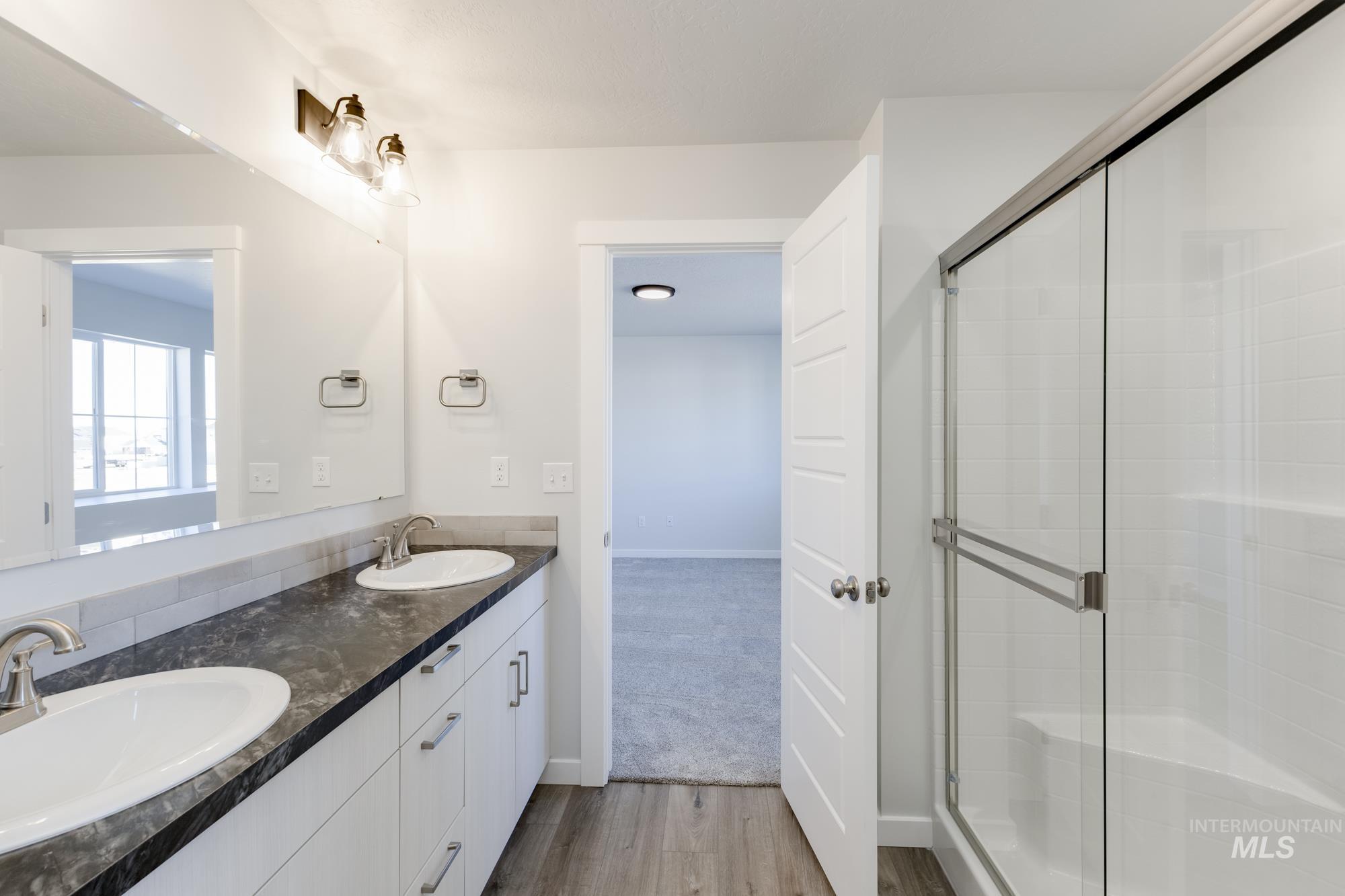 Full bathroom with wood finished floors, double vanity, and a shower with door