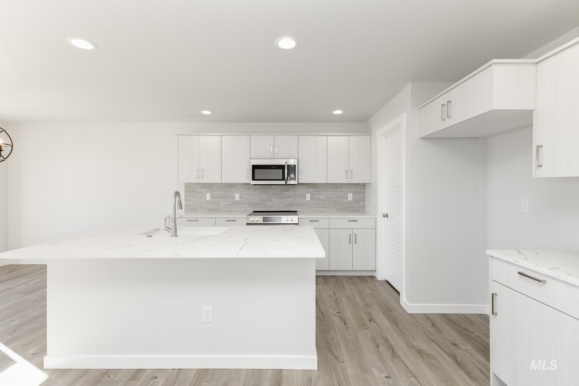 Kitchen with white cabinetry, light wood-style flooring, light stone countertops, and recessed lighting
