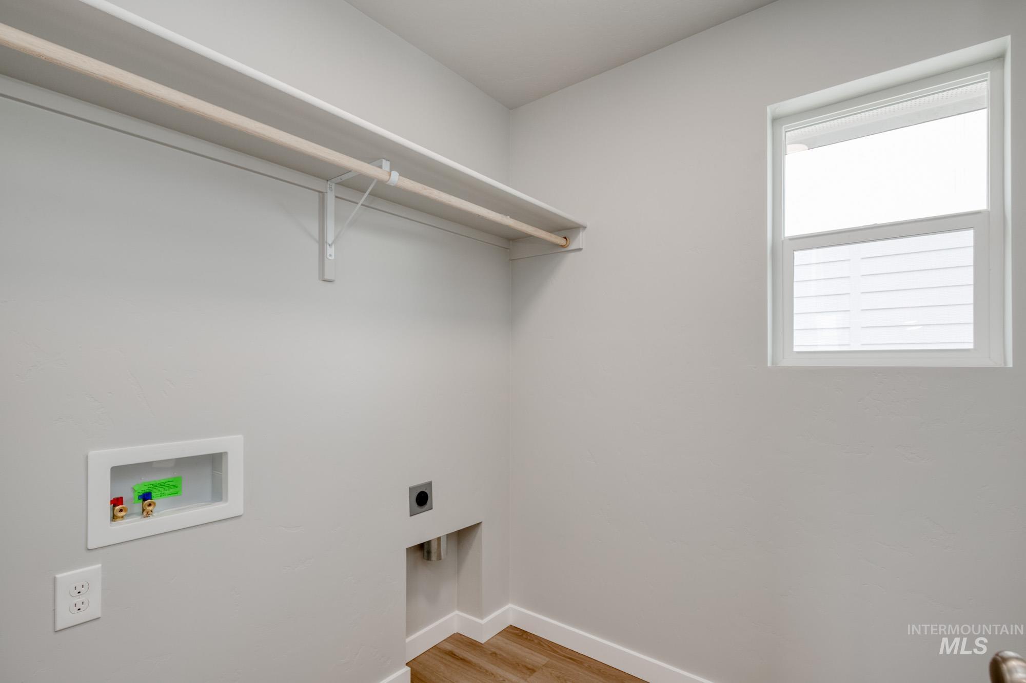 Washroom with hookup for an electric dryer, hookup for a washing machine, and light wood finished floors