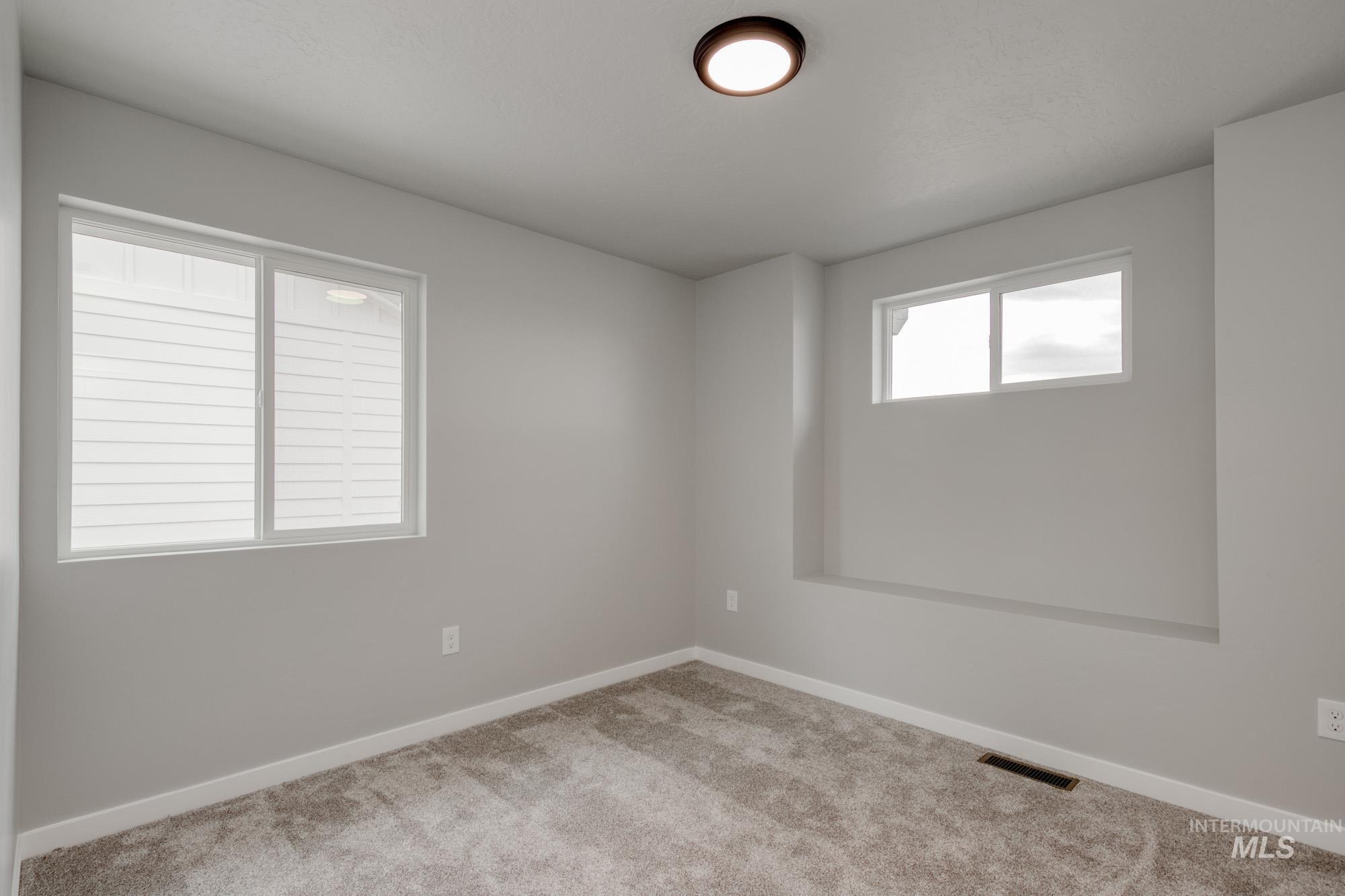 Spare room featuring carpet flooring and baseboards