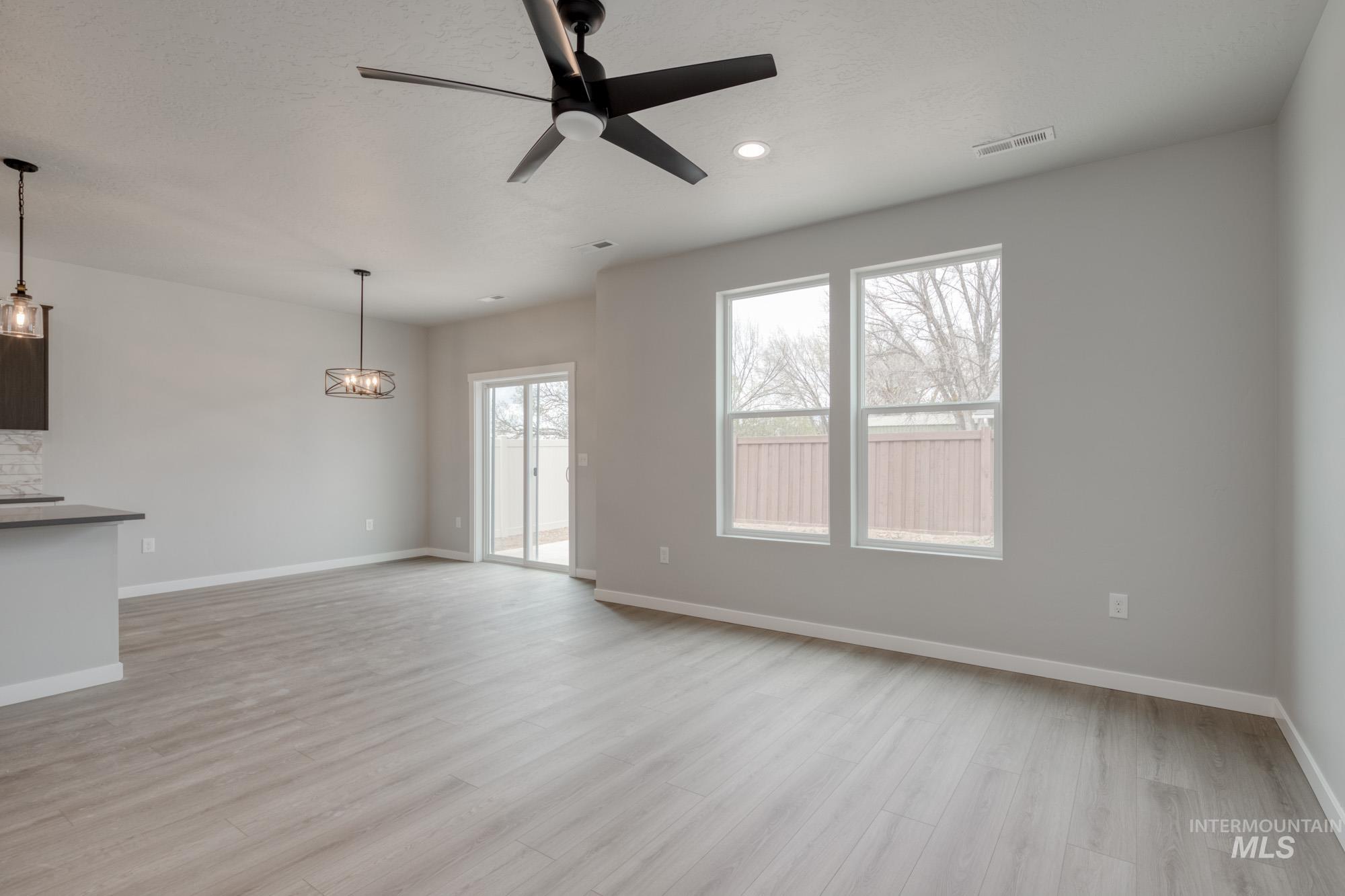 Unfurnished living room with ceiling fan, light wood-type flooring, a chandelier, and recessed lighting