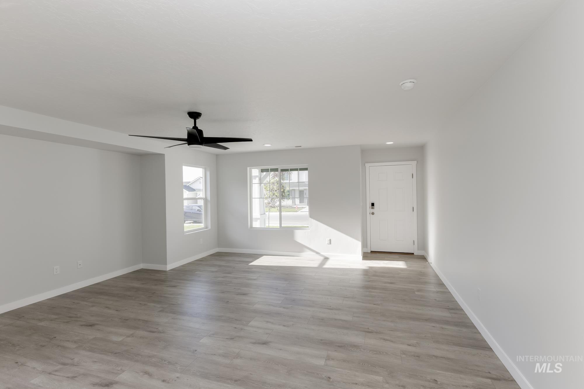 Unfurnished living room featuring light wood-style floors, a ceiling fan, and recessed lighting
