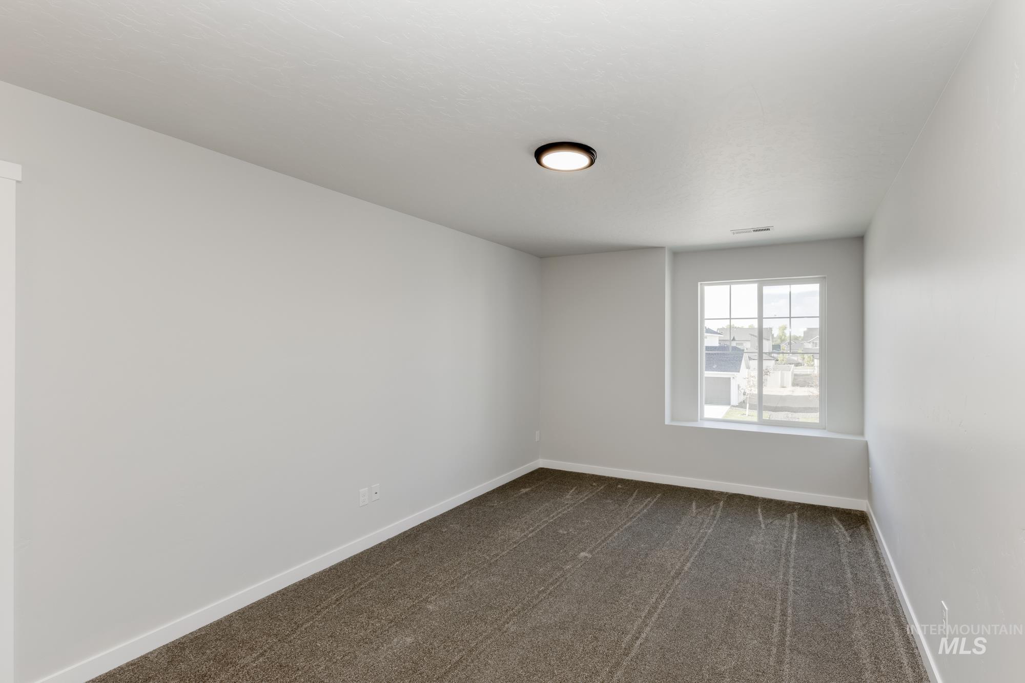 Spare room with dark colored carpet and baseboards