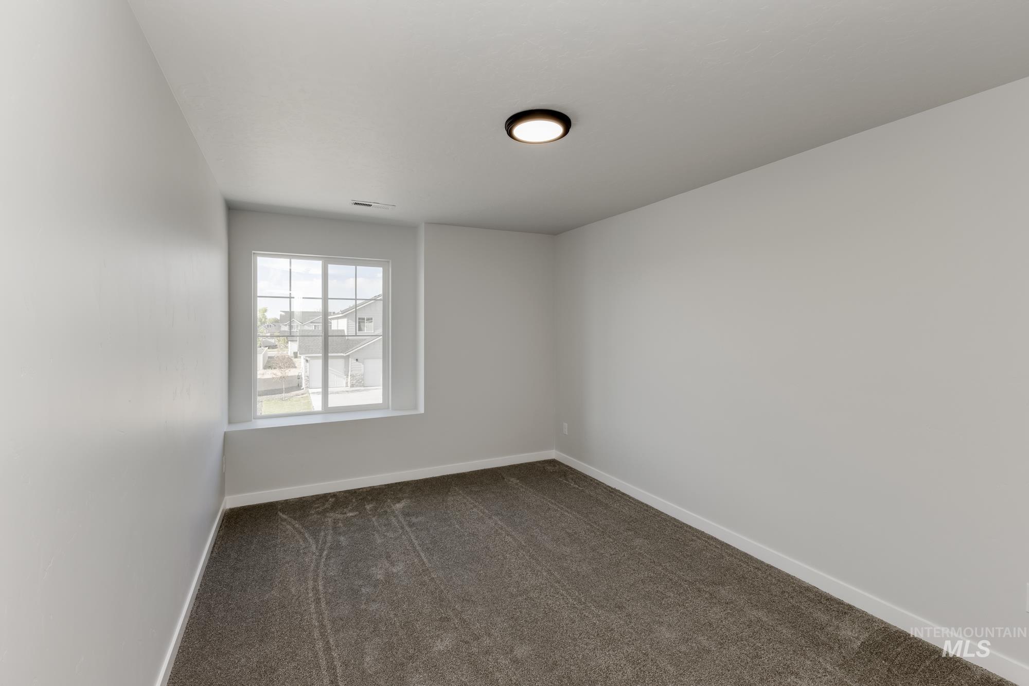 Empty room featuring dark carpet and baseboards