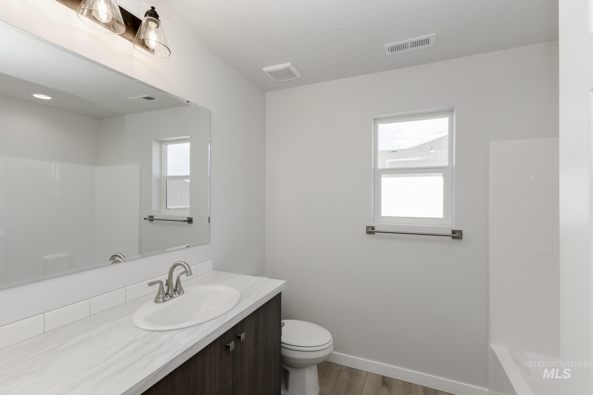 Full bathroom featuring vanity, wood finished floors, and washtub / shower combination