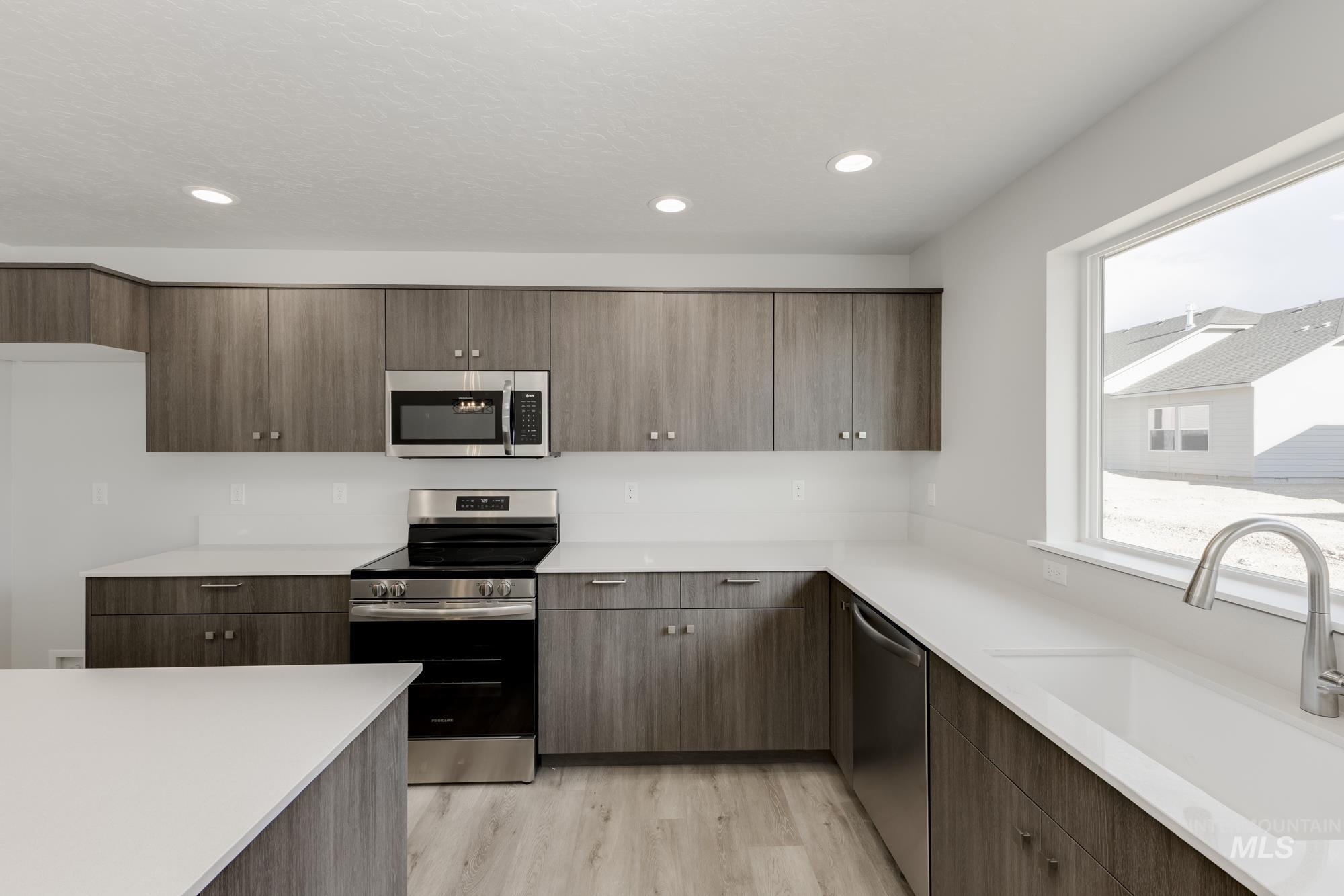 Kitchen with stainless steel appliances, light countertops, light wood-style floors, recessed lighting, and modern cabinets