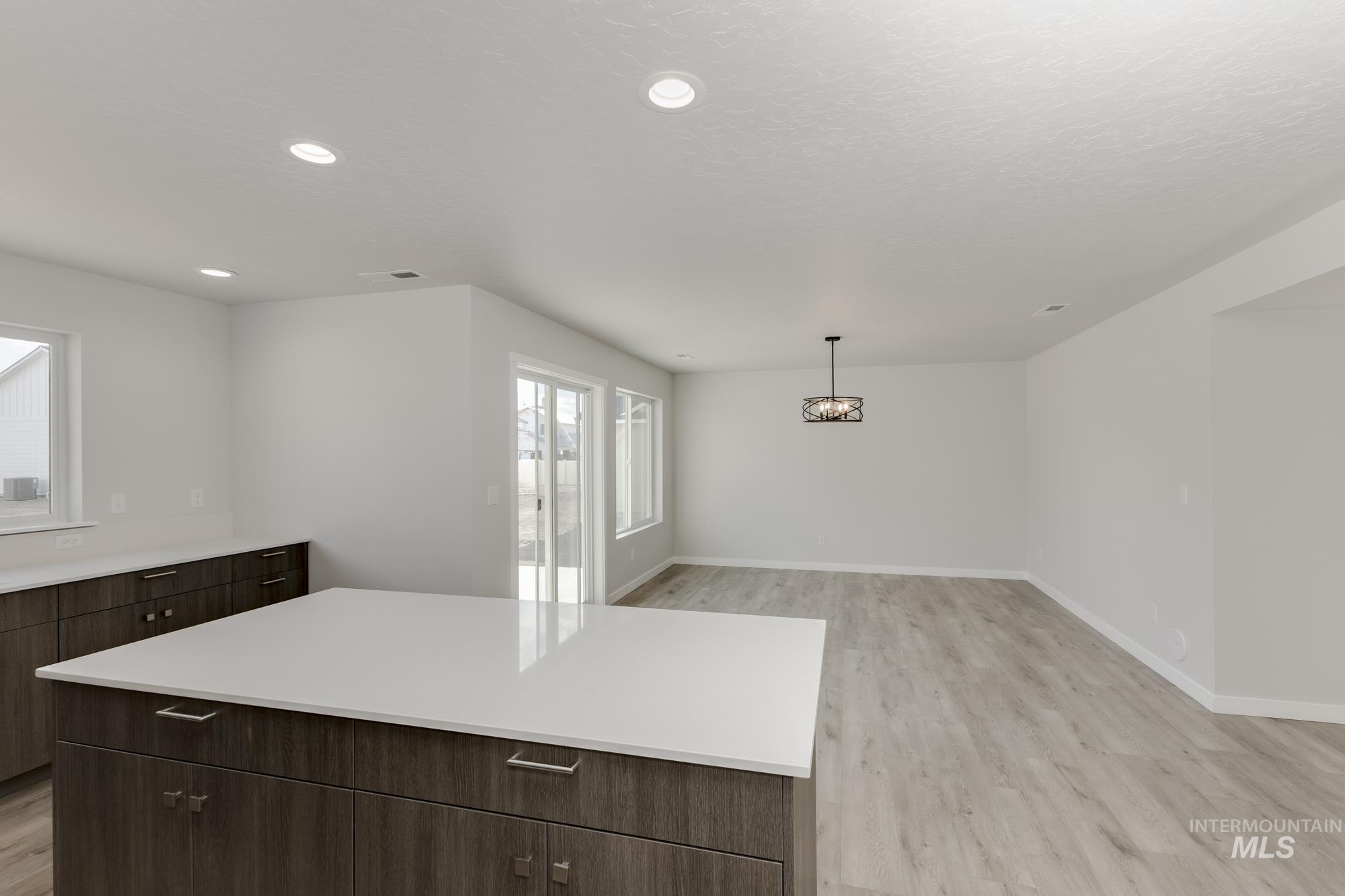Kitchen featuring light countertops, light wood finished floors, modern cabinets, a center island, and dark brown cabinetry