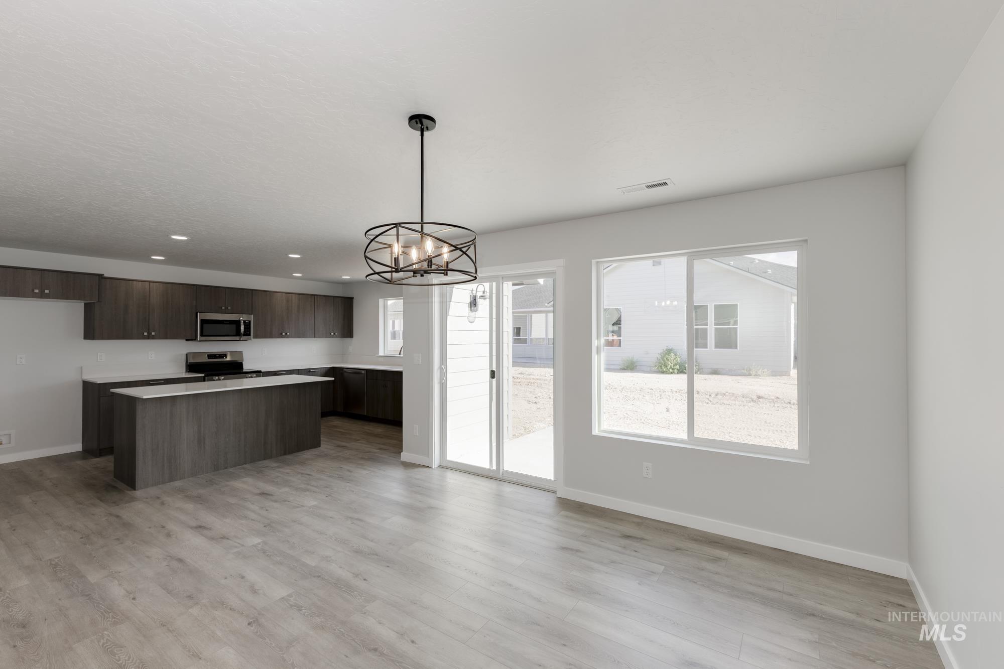 Kitchen with a kitchen island, a chandelier, dark brown cabinets, light countertops, and stainless steel appliances