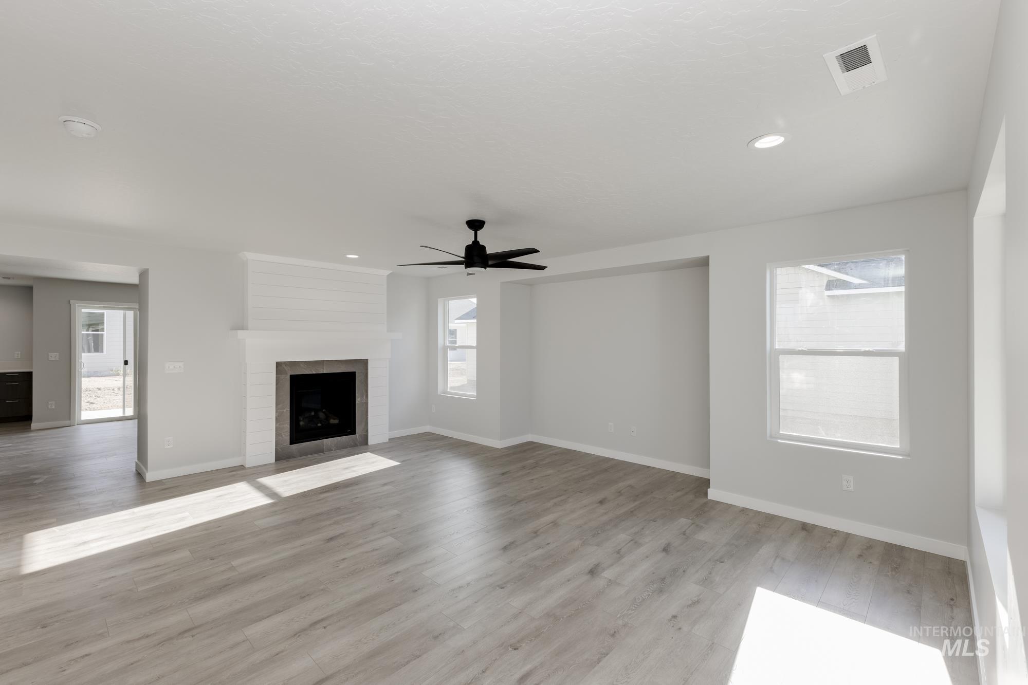 Unfurnished living room with ceiling fan, light wood-style floors, a large fireplace, and recessed lighting