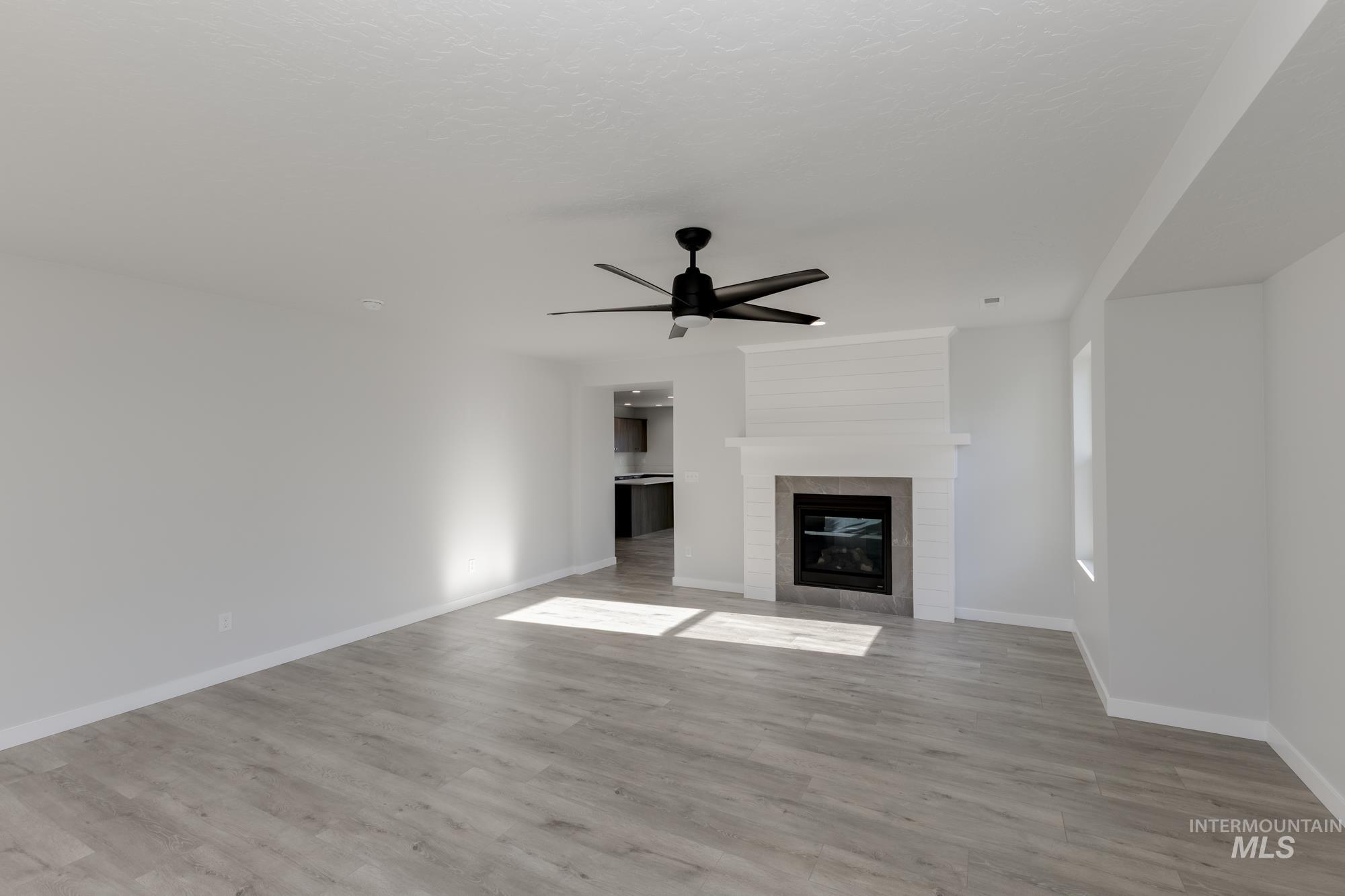 Unfurnished living room featuring wood finished floors, a ceiling fan, and a fireplace