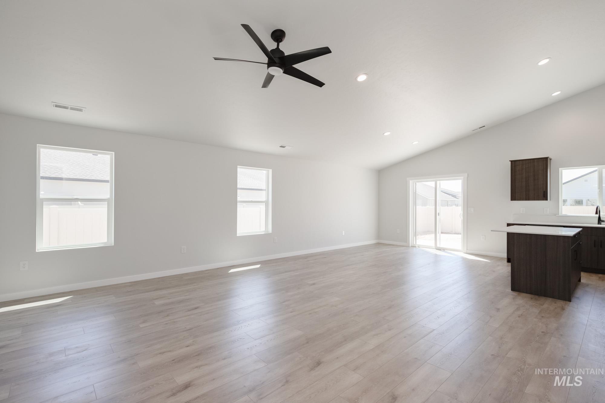 Unfurnished living room with vaulted ceiling, a ceiling fan, light wood-type flooring, and recessed lighting
