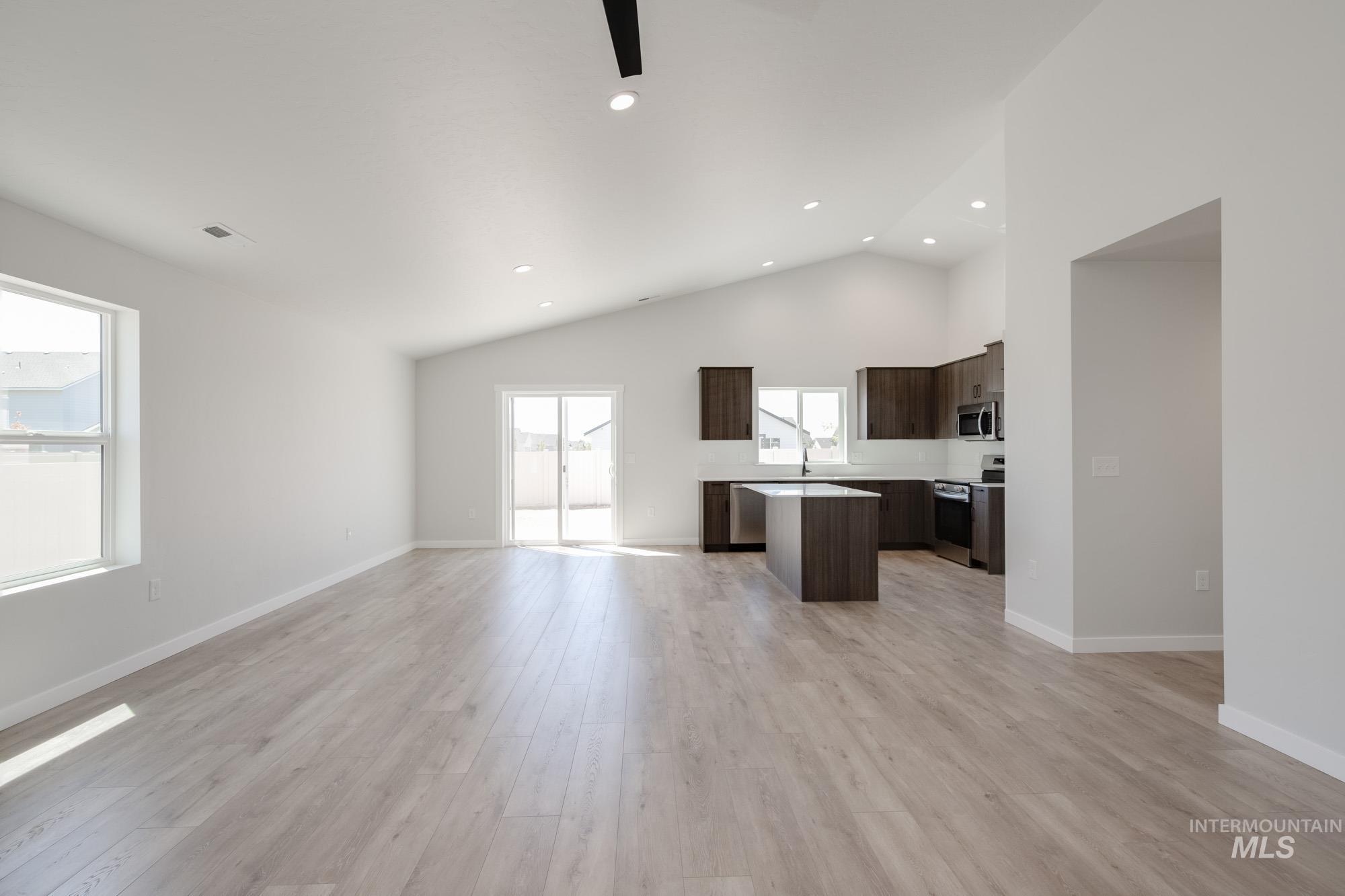 Unfurnished living room featuring light wood finished floors, ceiling fan, recessed lighting, and high vaulted ceiling
