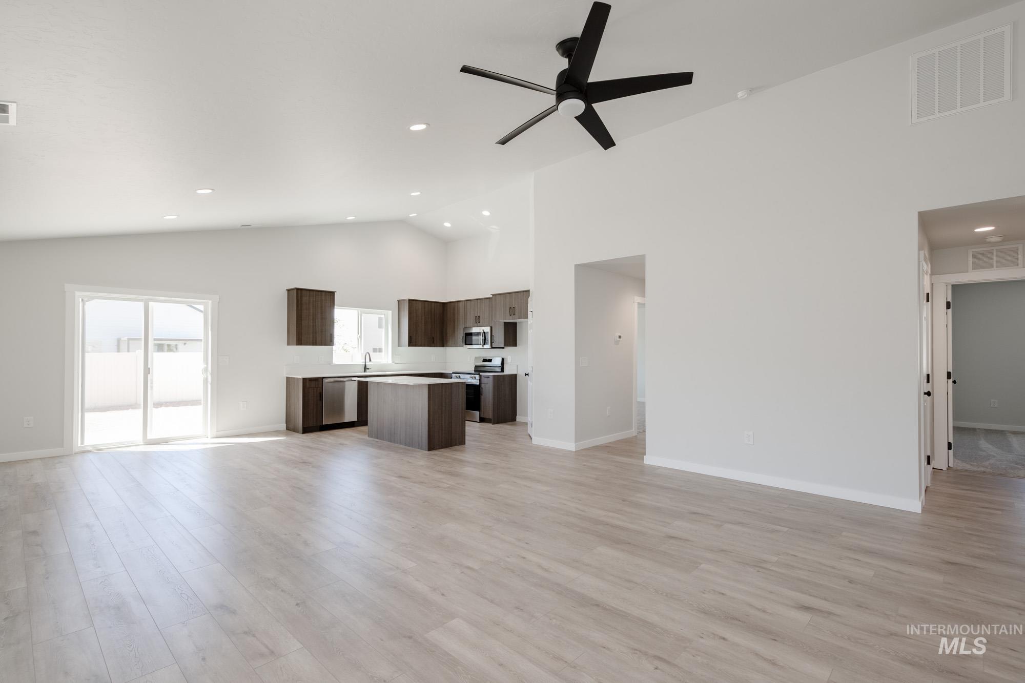 Unfurnished living room with light wood-type flooring, high vaulted ceiling, a ceiling fan, and recessed lighting