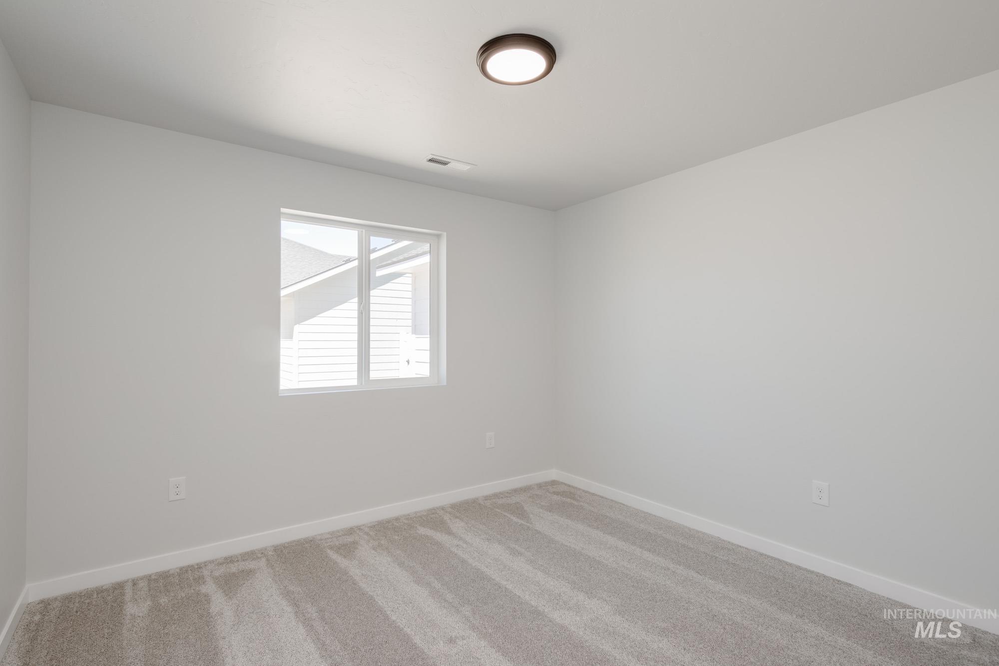 Unfurnished room featuring light carpet and baseboards
