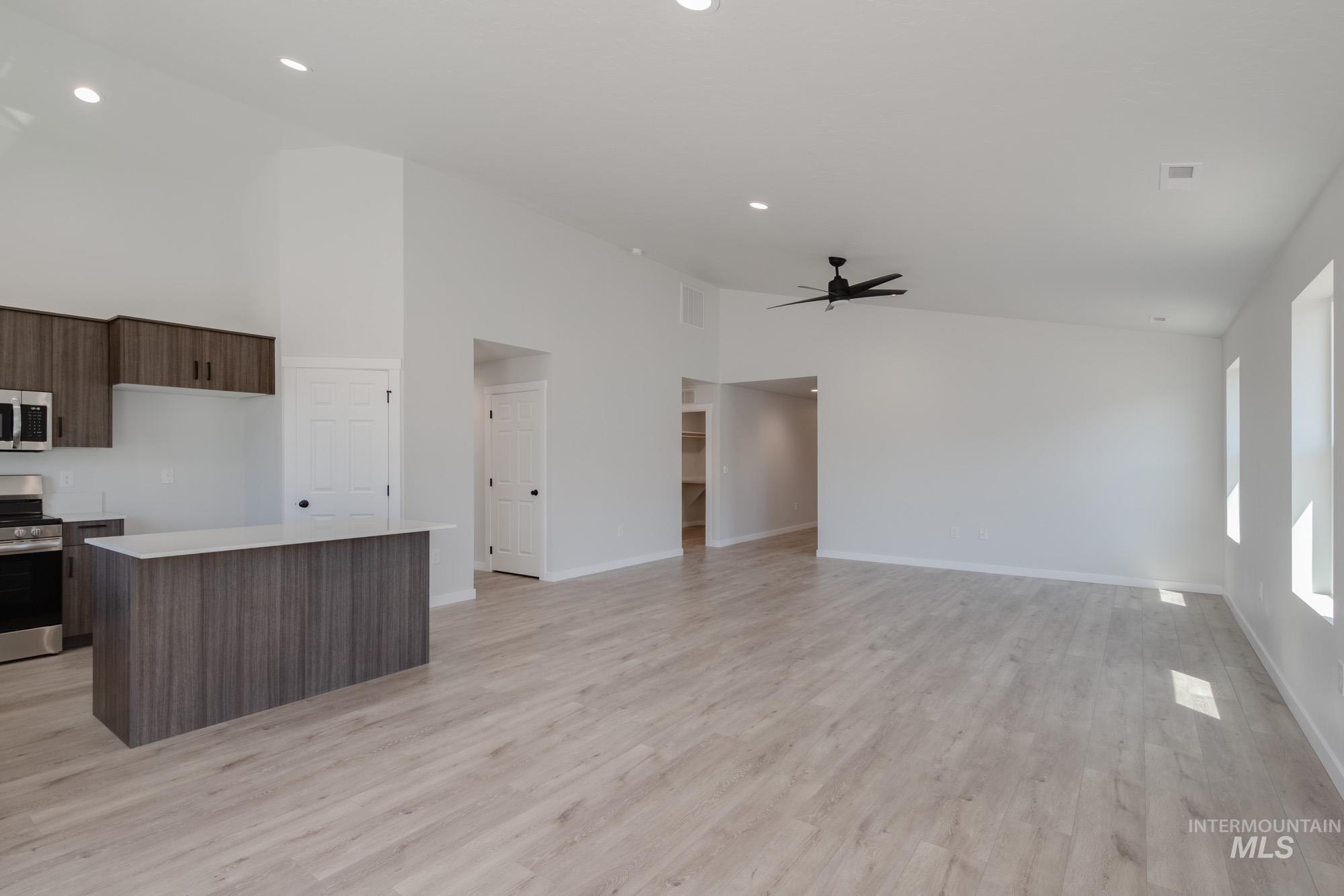 Kitchen with appliances with stainless steel finishes, light countertops, a center island, light wood-style flooring, and ceiling fan