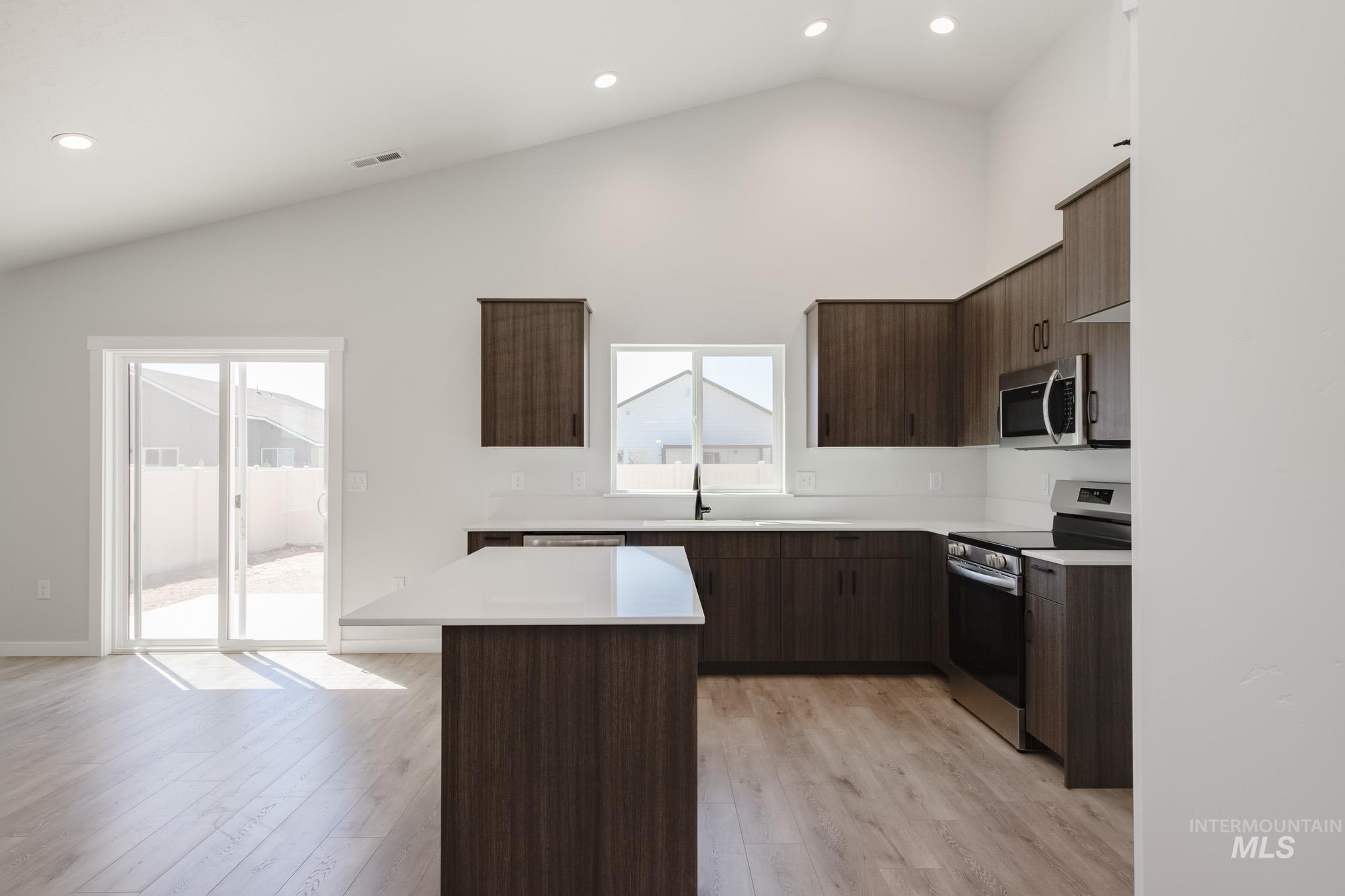Kitchen with stainless steel appliances, a kitchen island, light countertops, recessed lighting, and modern cabinets