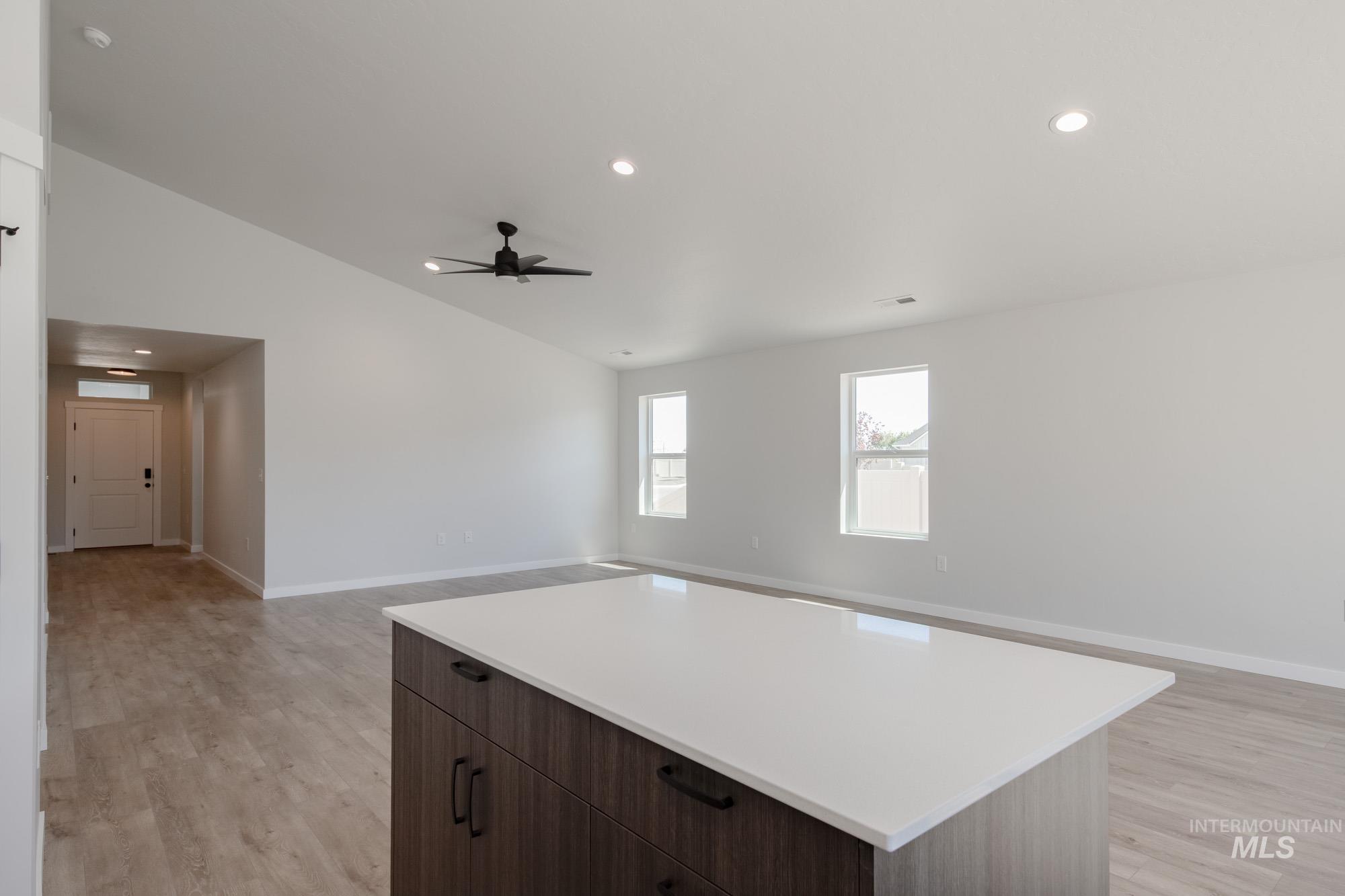 Kitchen featuring open floor plan, light wood-type flooring, recessed lighting, lofted ceiling, and light countertops