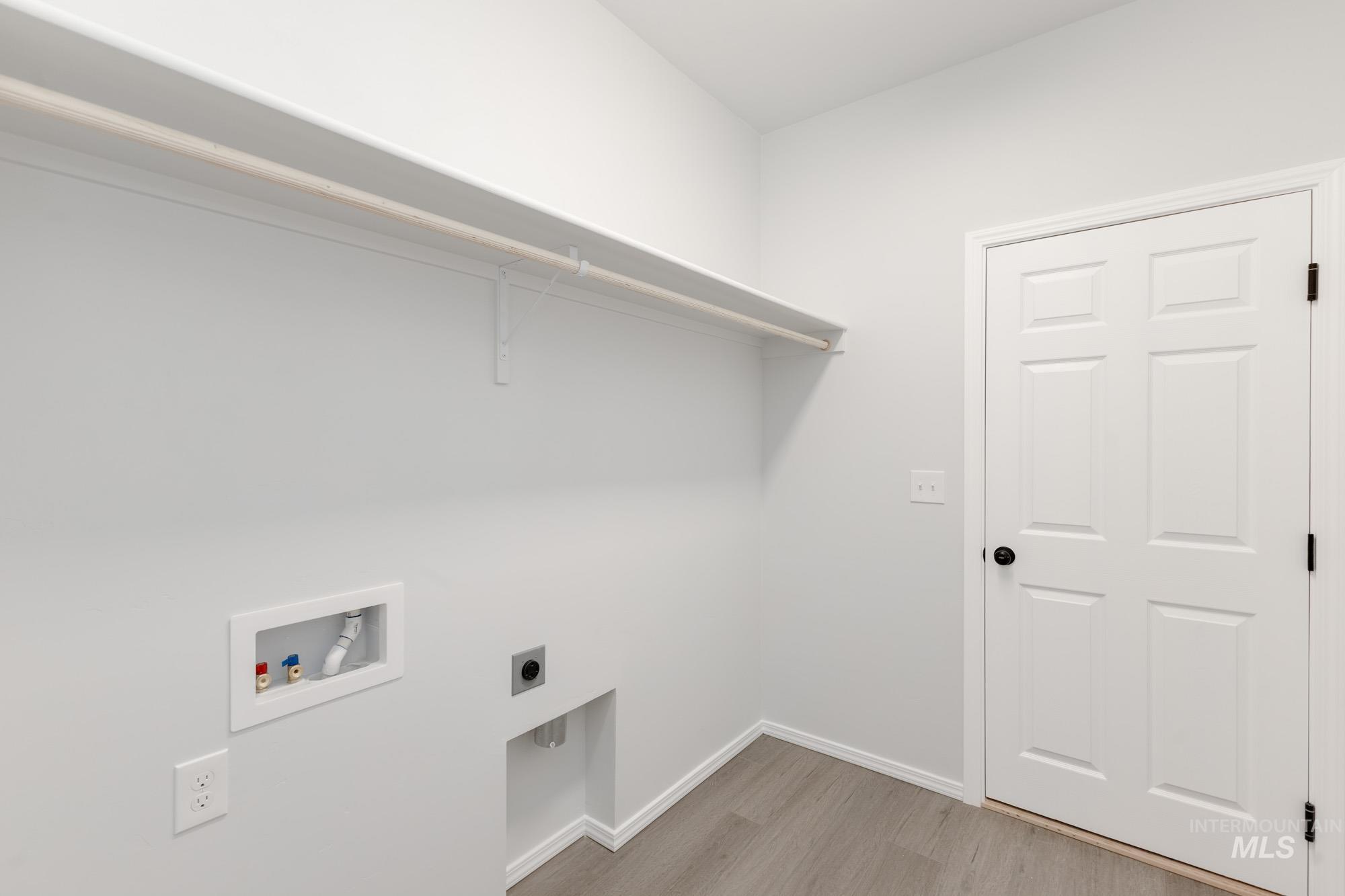 Laundry area with light wood-type flooring, electric dryer hookup, and hookup for a washing machine